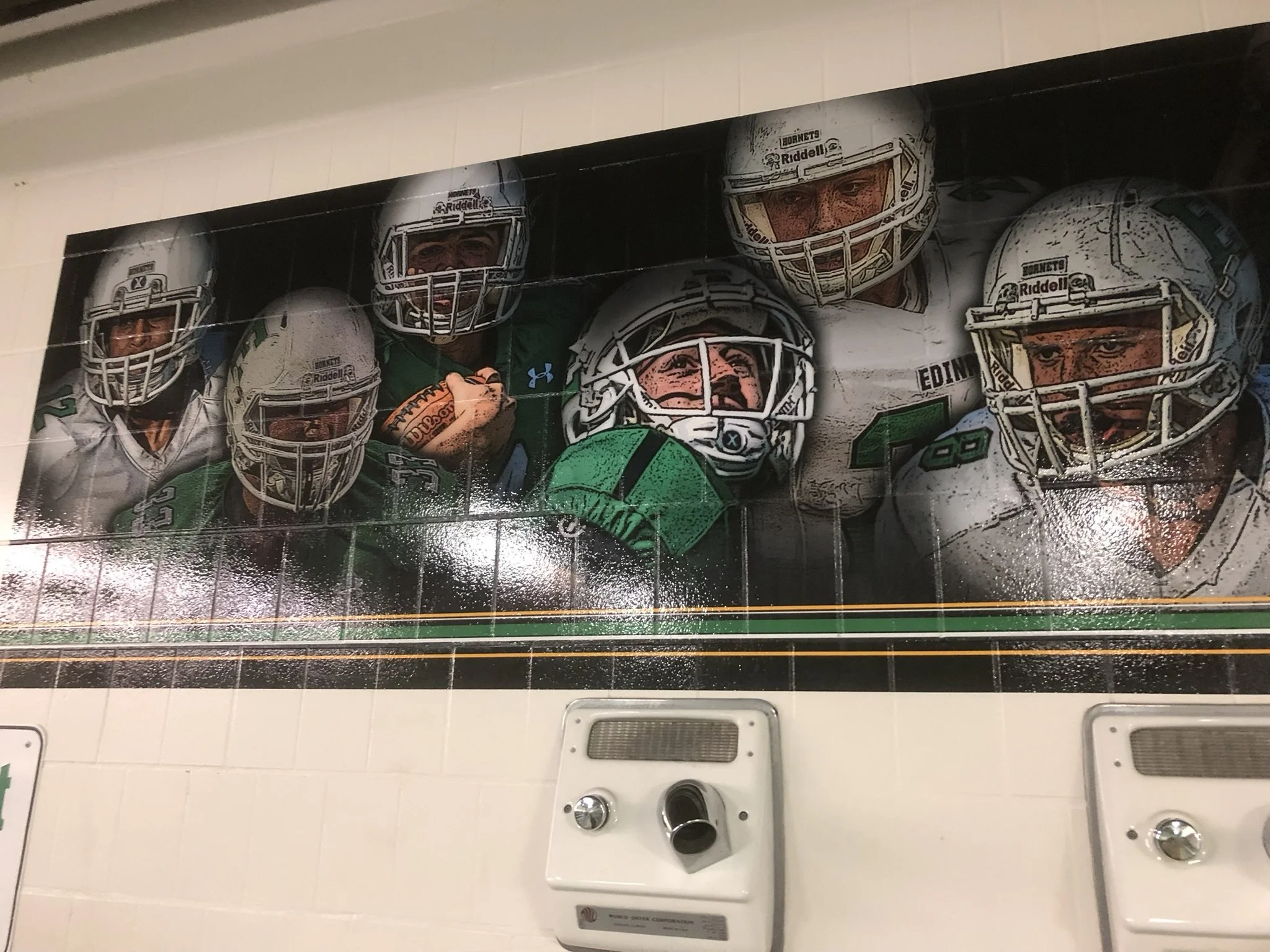 A framed poster of a football team with players wearing helmets, some with green jerseys, arranged in a group shot.