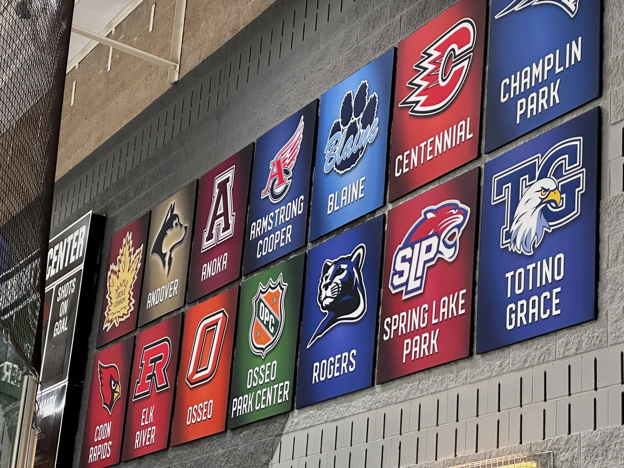 School sports banners showing team logos and names, including Armstrong Cooper, Blaine, Centennial, Champlin Park, Andover, Anoka, Coon Rapids, Elk River, Osseo, Rogers, Spring Lake Park, and Totino Grace.