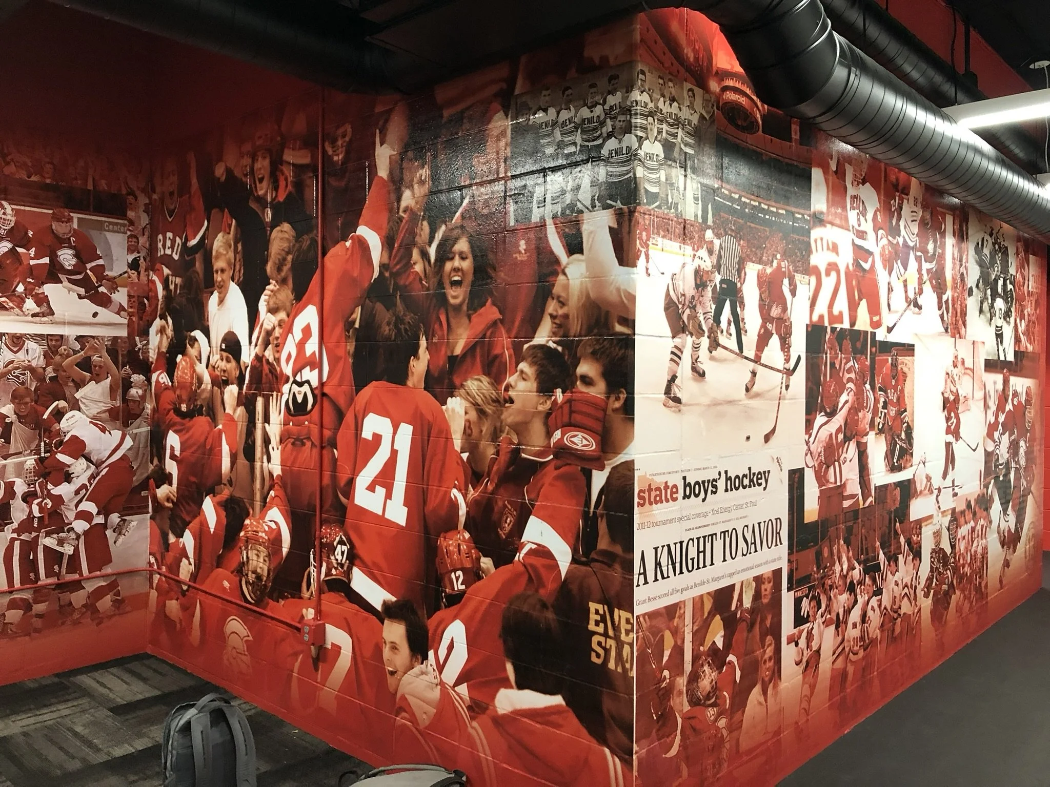 A collage of hockey moments and team celebrations on a wall with dominant red color, including players, fans, and referees, with a newspaper clipping titled 'A Knight to Savor' about a hockey game.