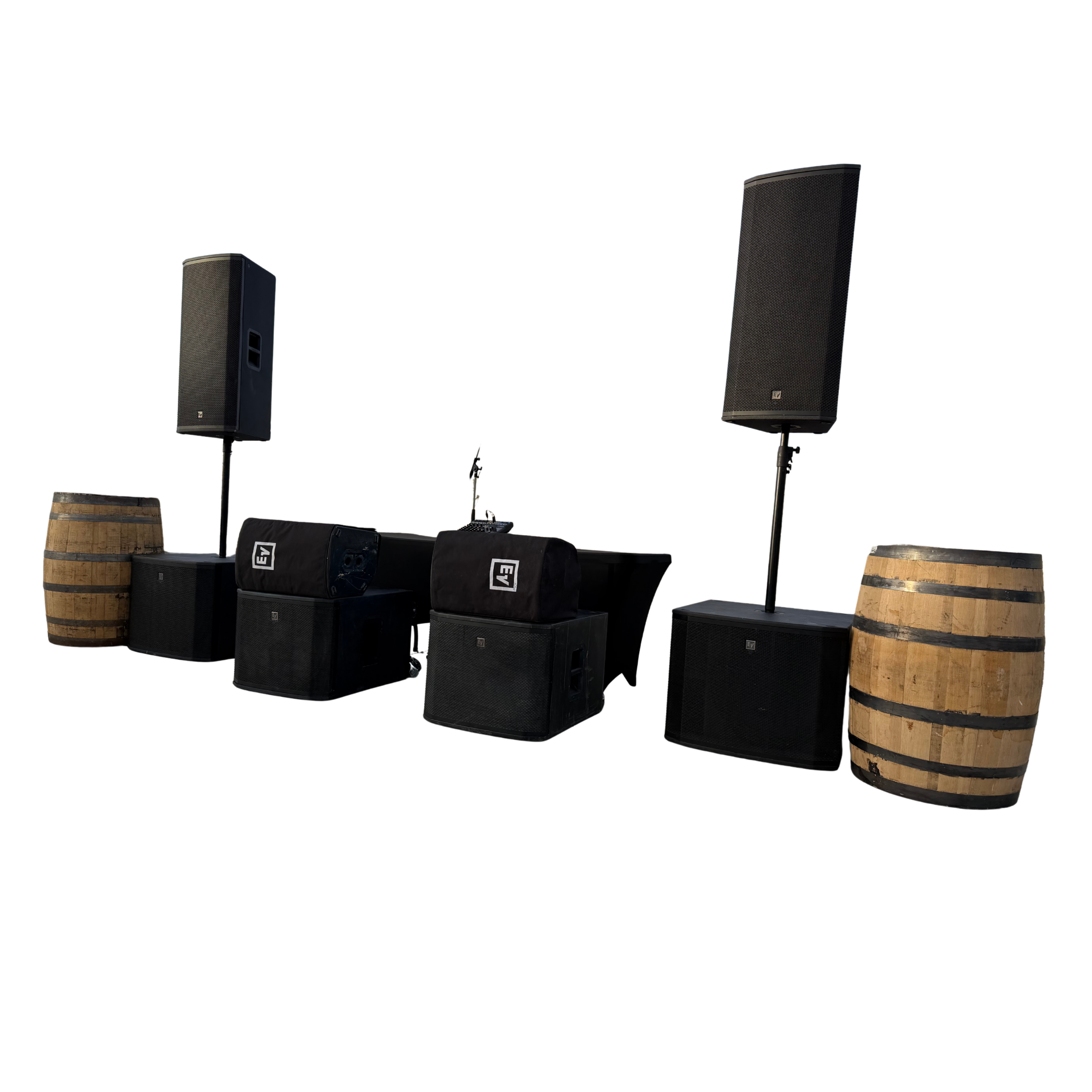 Audio speakers, DJ equipment, and wooden barrel tables arranged in a setup for event or performance.