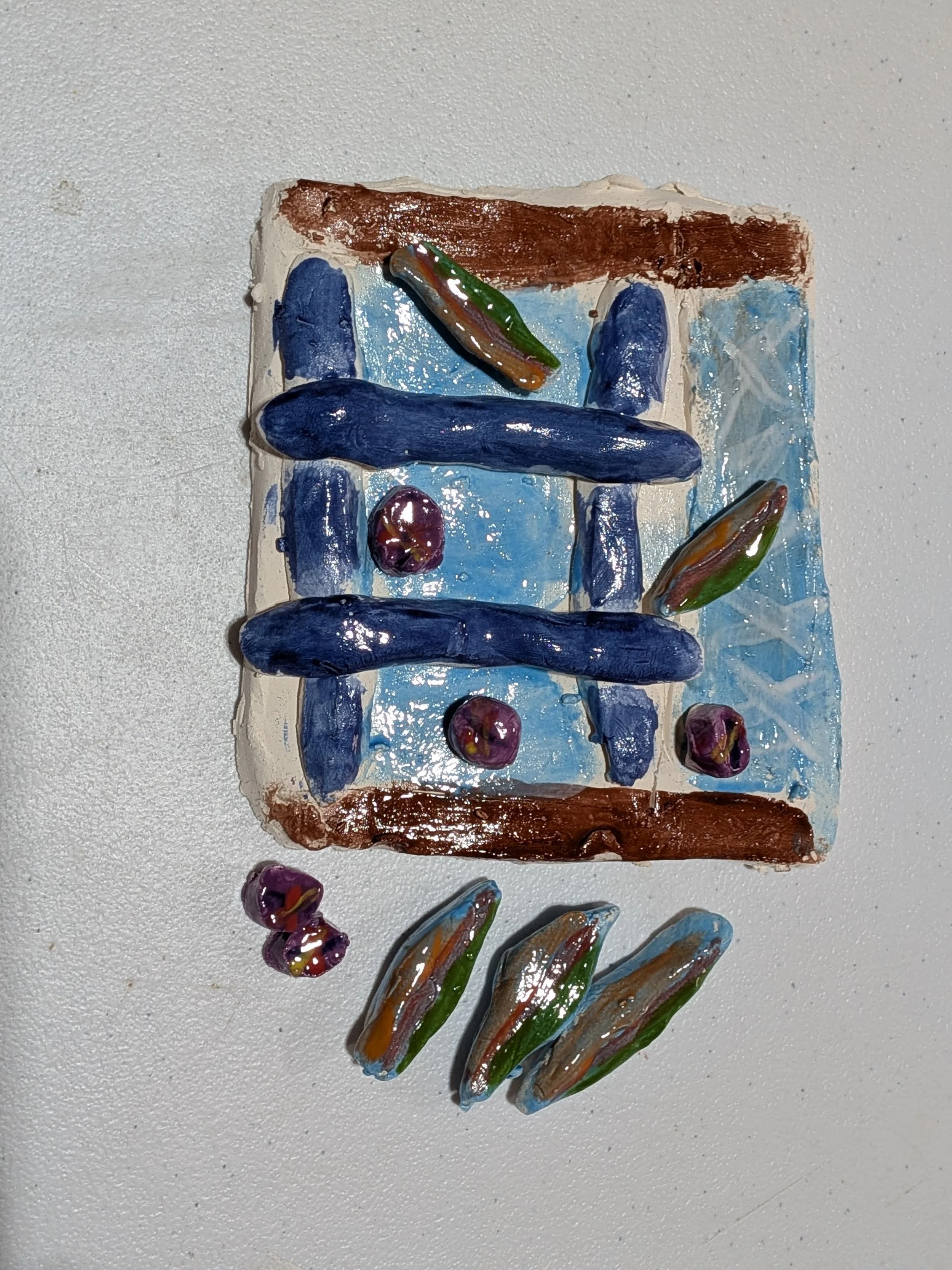 Colorful glass art of a window with blue and brown accents, surrounded by smaller colorful glass pieces.