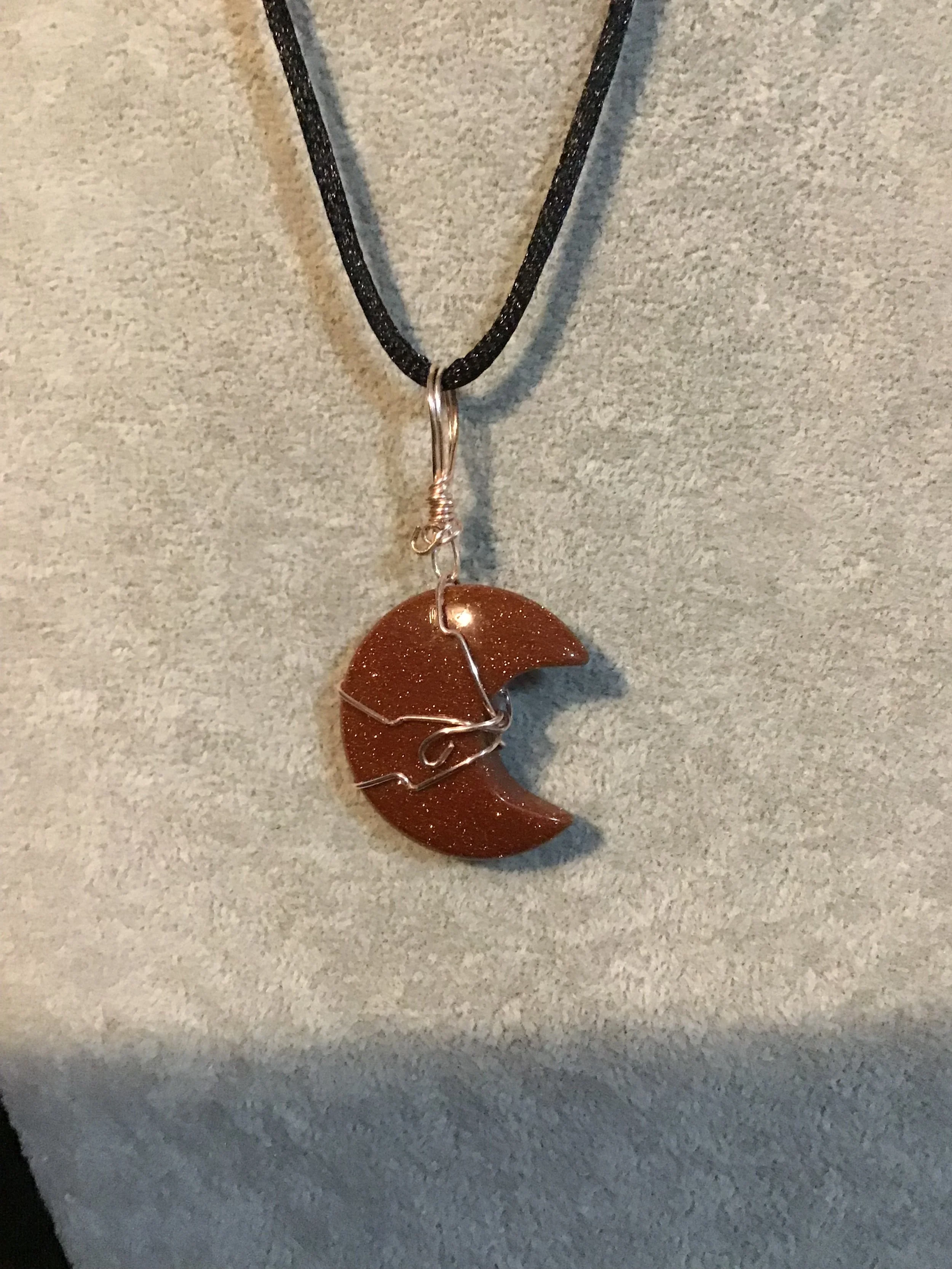Wire wrapped Gold Red Sandstone crescent moon on a black satin cord