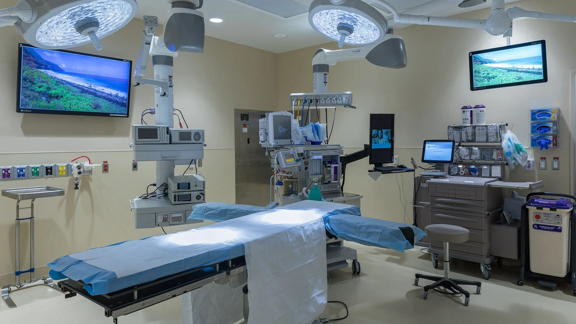 Modern hospital operating room equipped with surgical lights, monitors, medical devices, and an operating table prepared for surgery.
