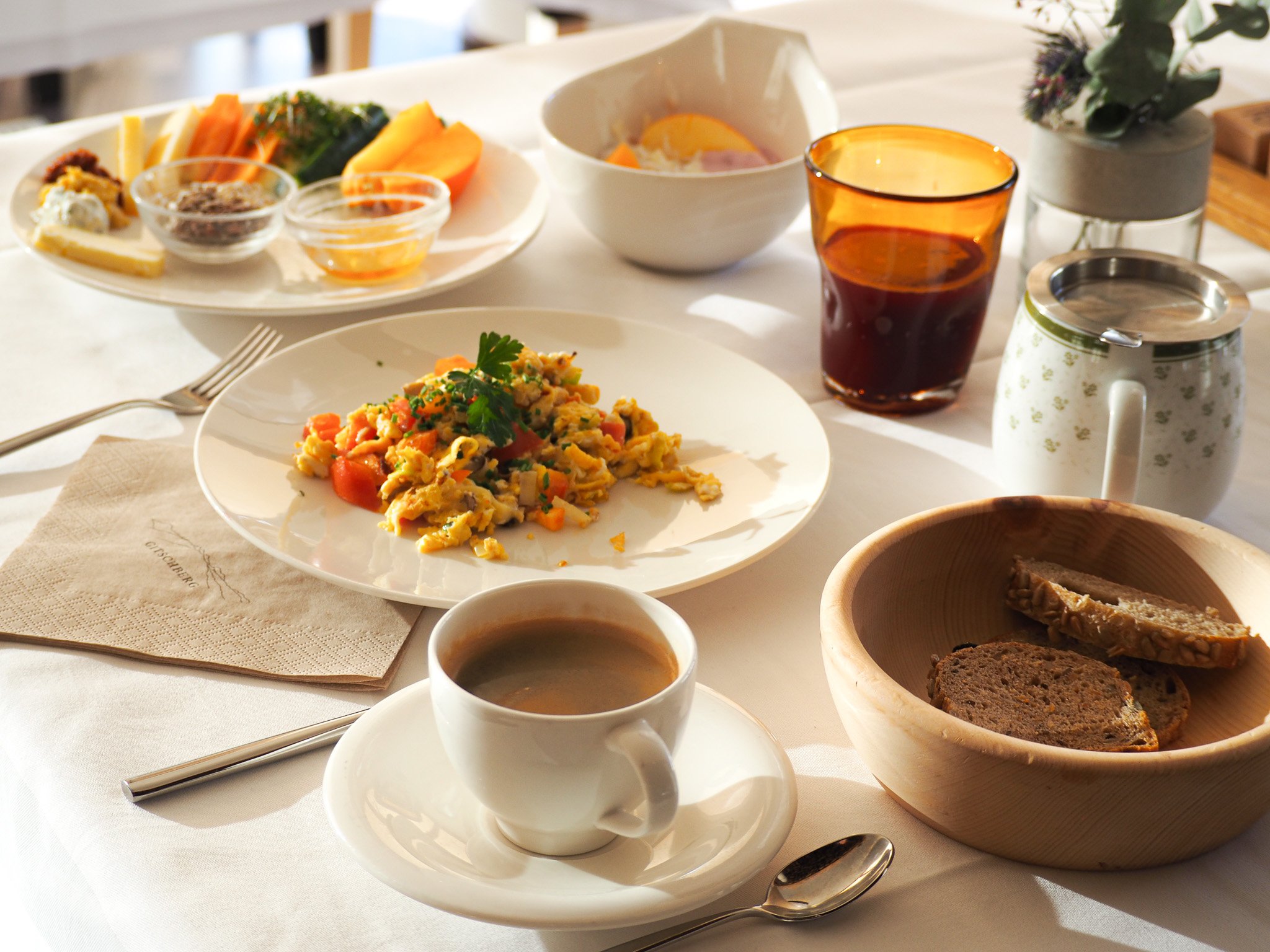 Frühstückstisch mit Kaffee, Eiern, Brot, Saft, Joghurt und verschiedenen Beilagen