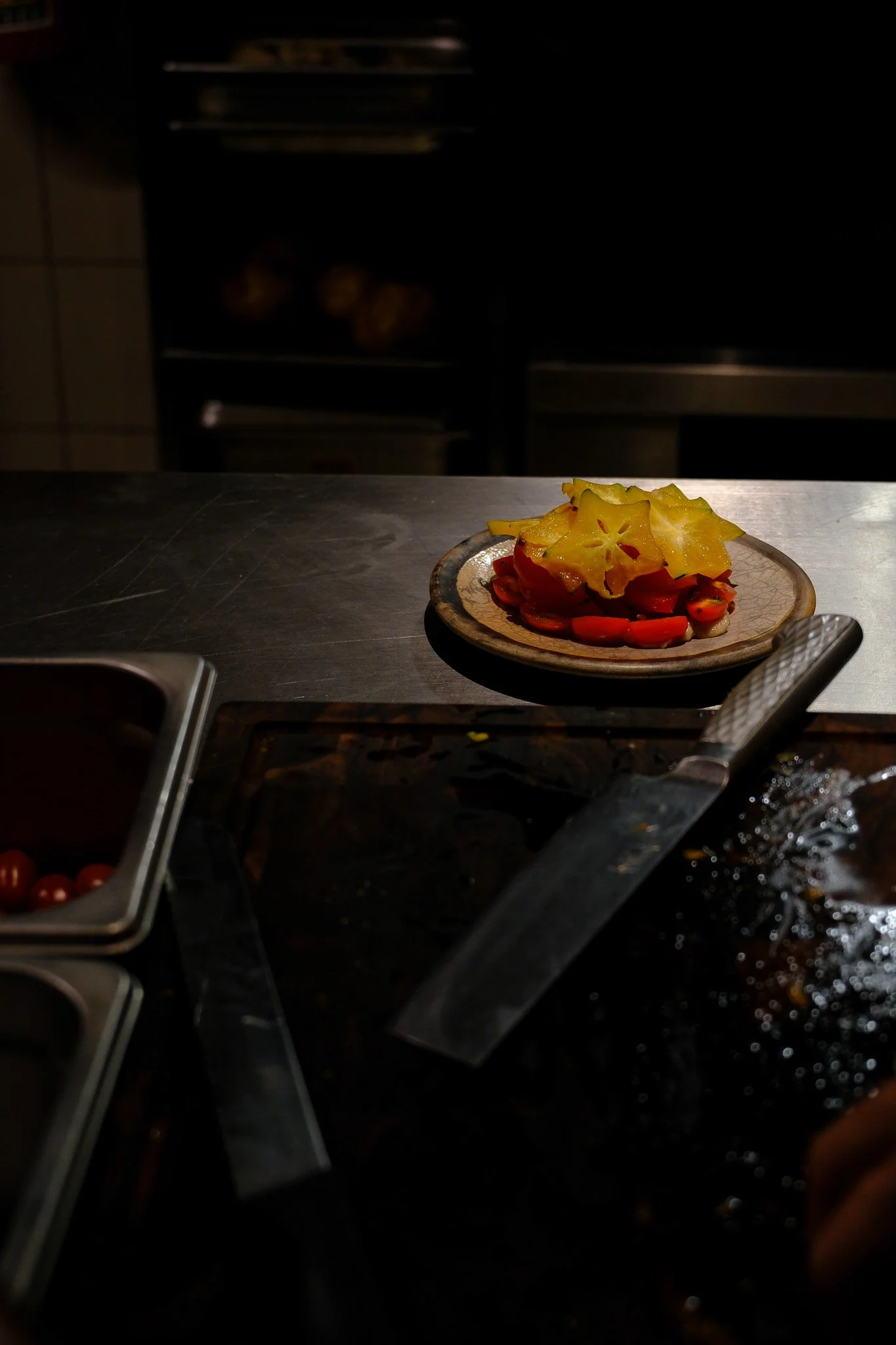 Bunte aufgeschnittene Tomaten und gelbe Paprika auf einem kleinen Teller in einer Küche.
