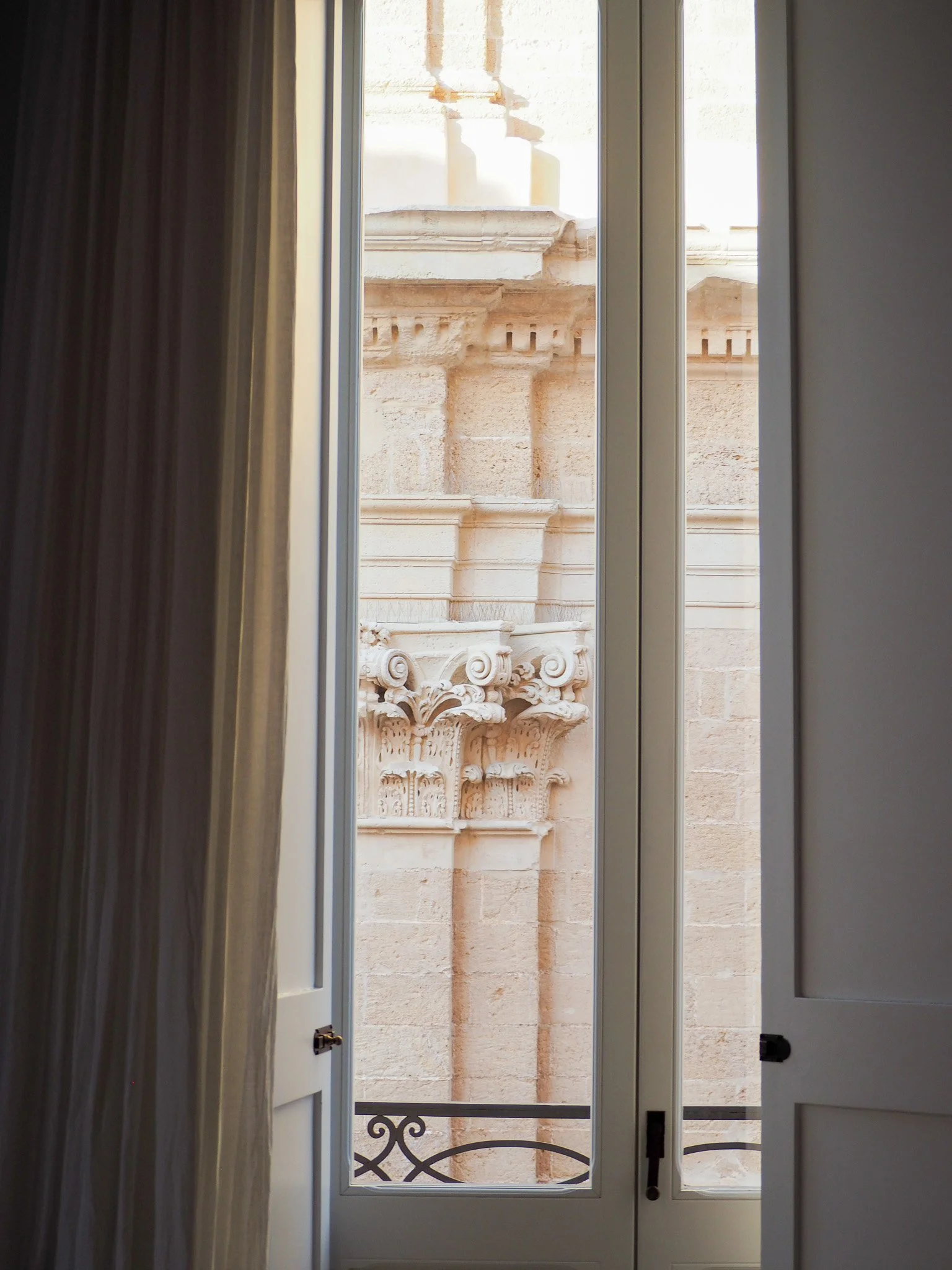Blick durch eine offene Fenster in ein historisches Gebäude mit architektonischen Details aus Stein.