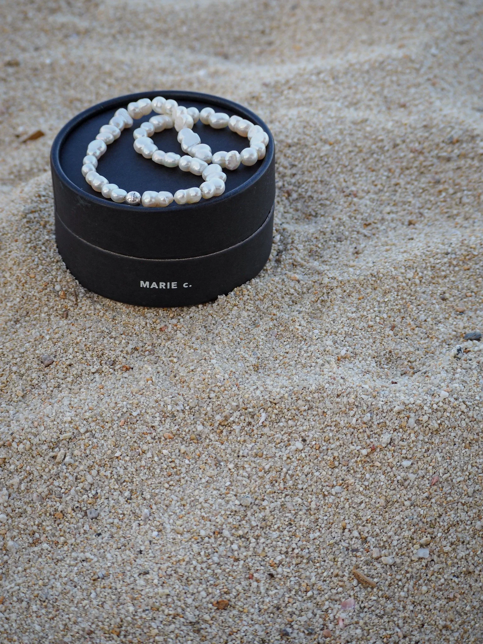 Perlenkette in einer schwarzen Schmuckschachtel auf Sand