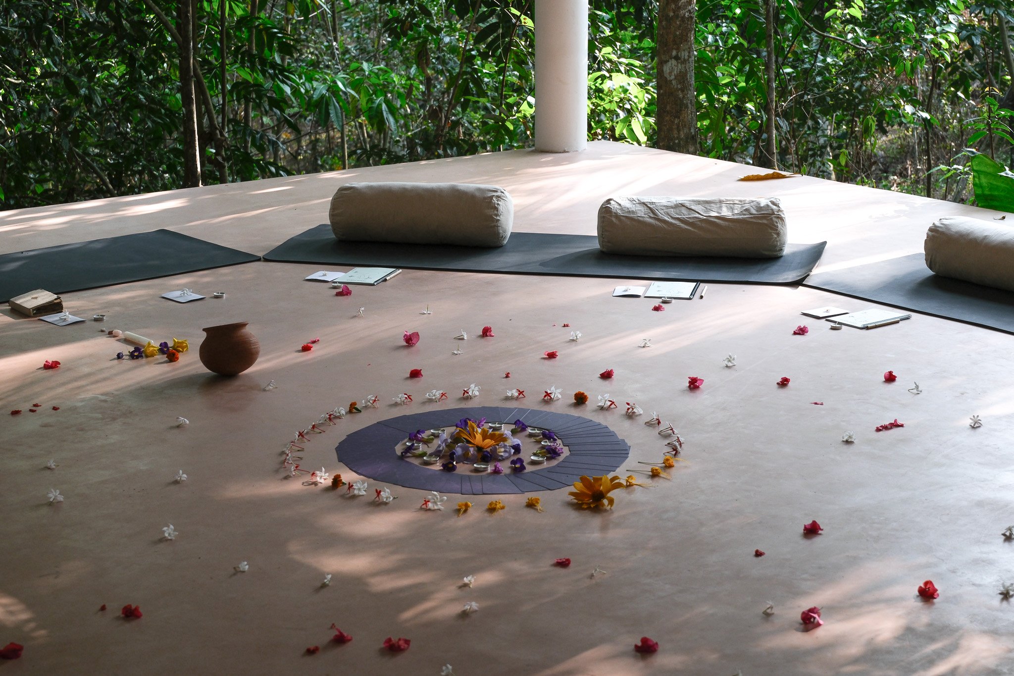 Ein Raum im Freien, mit Dekorationen aus Blumen, auf einem Holzboden, umgeben von grünen Bäumen.