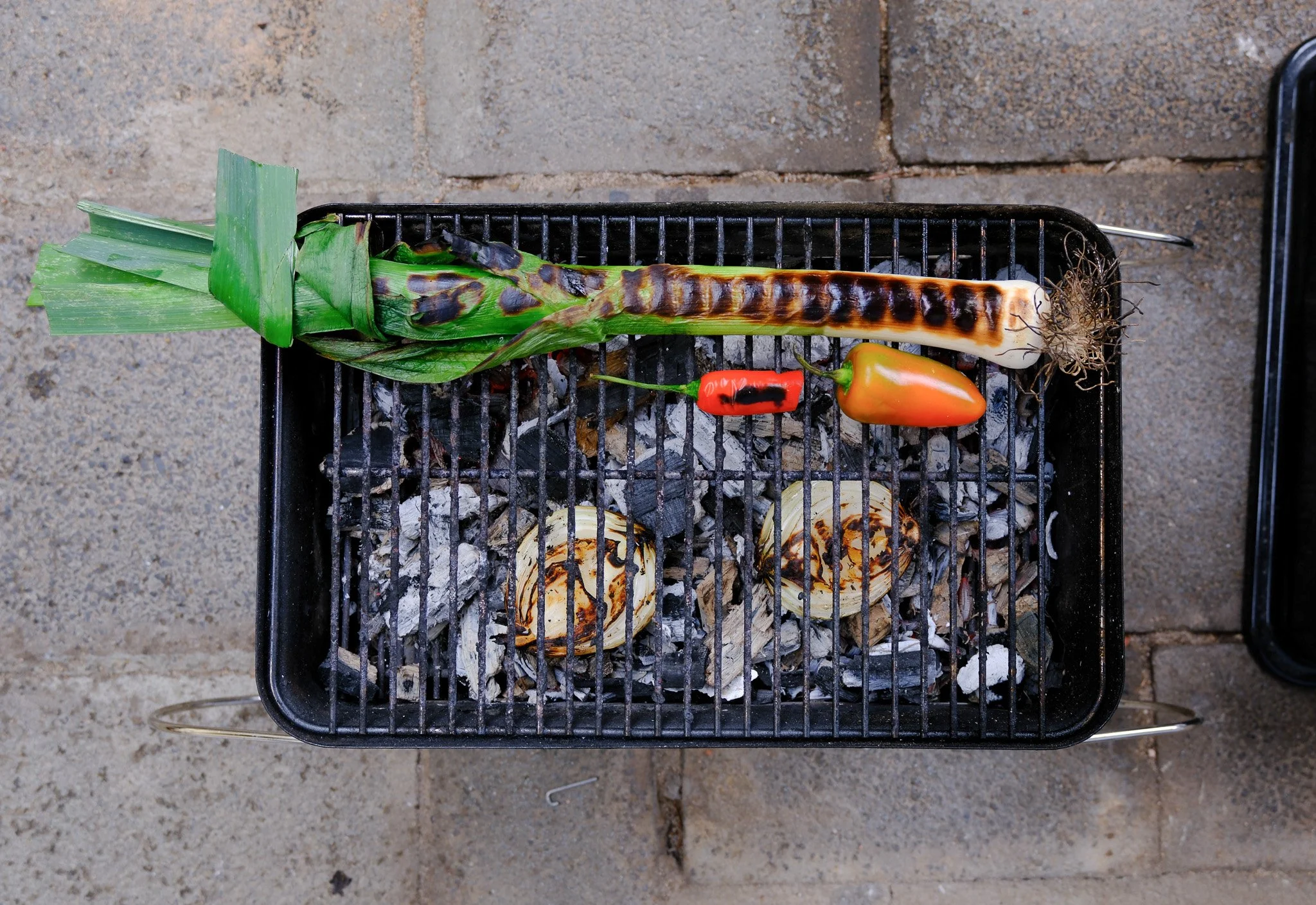 Grill mit Limetten, Chilischote, Paprika, Zwiebeln und einer gebrannten Tomate