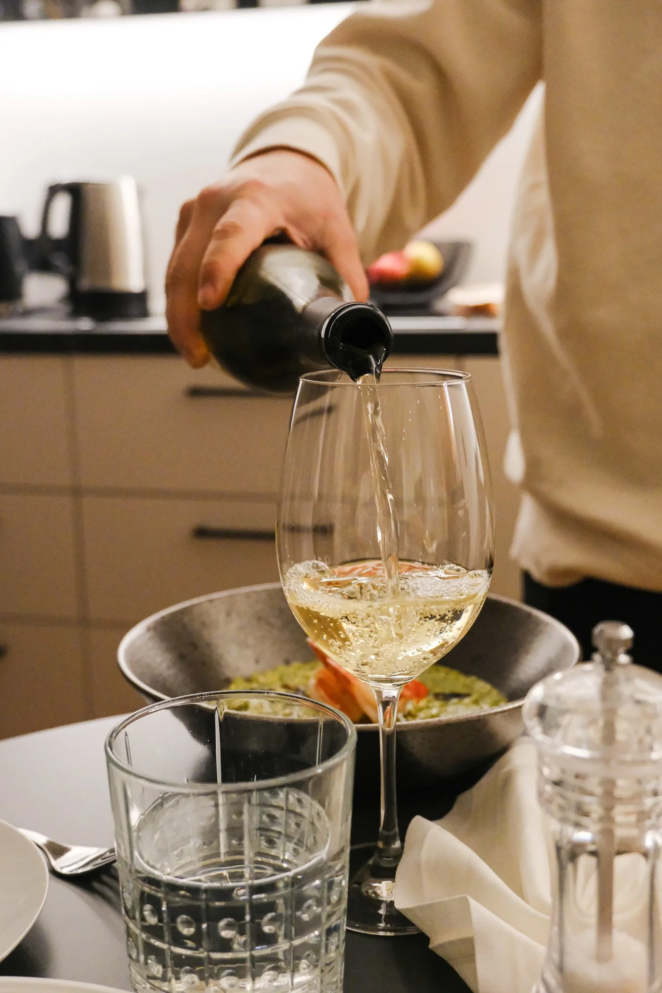 Ein Mann gießt weißen Wein in ein Weinglas bei einem Abendessen.