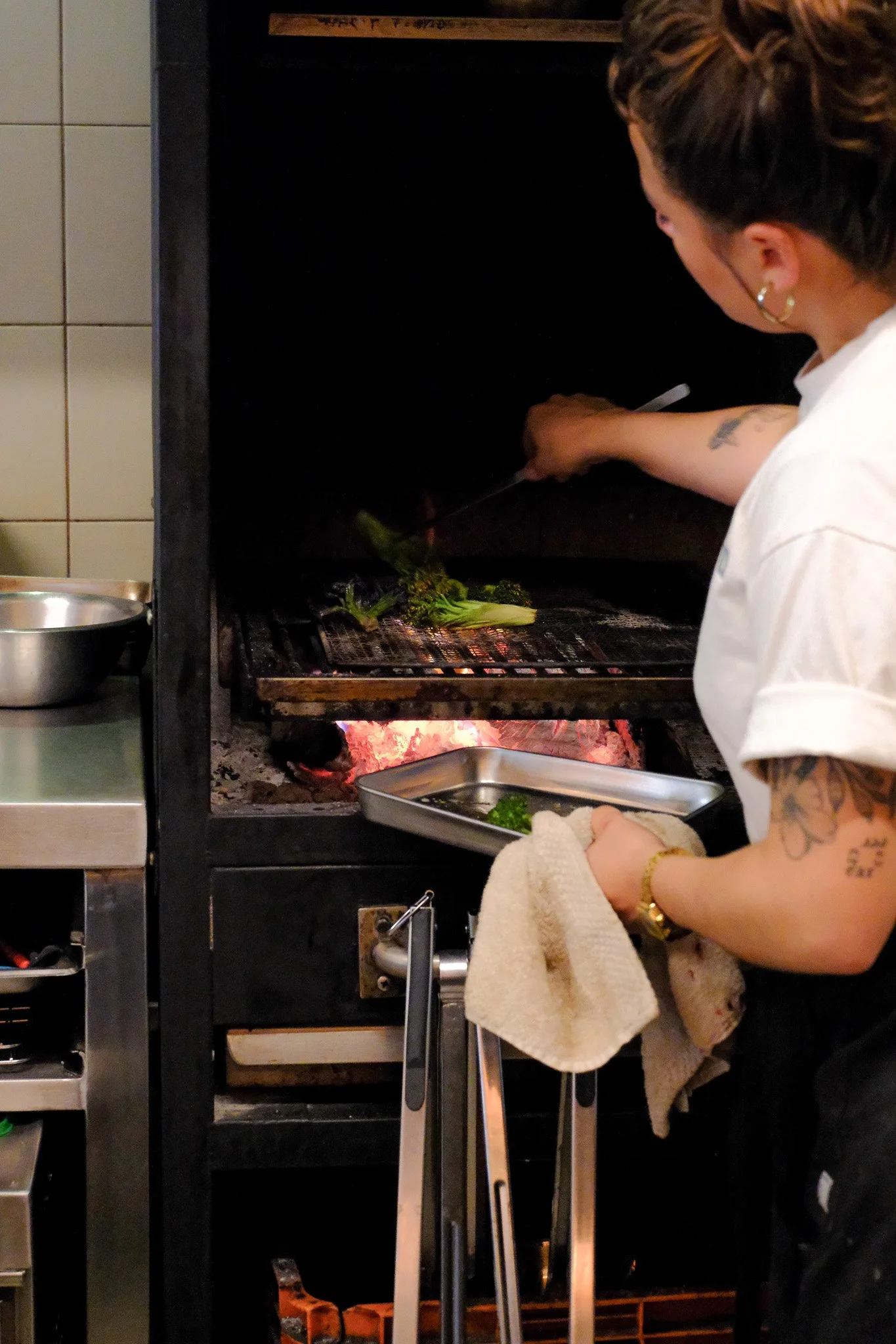 Eine Frau bereitet Gemüse auf einem Grill vor, während sie in einer Küche steht.