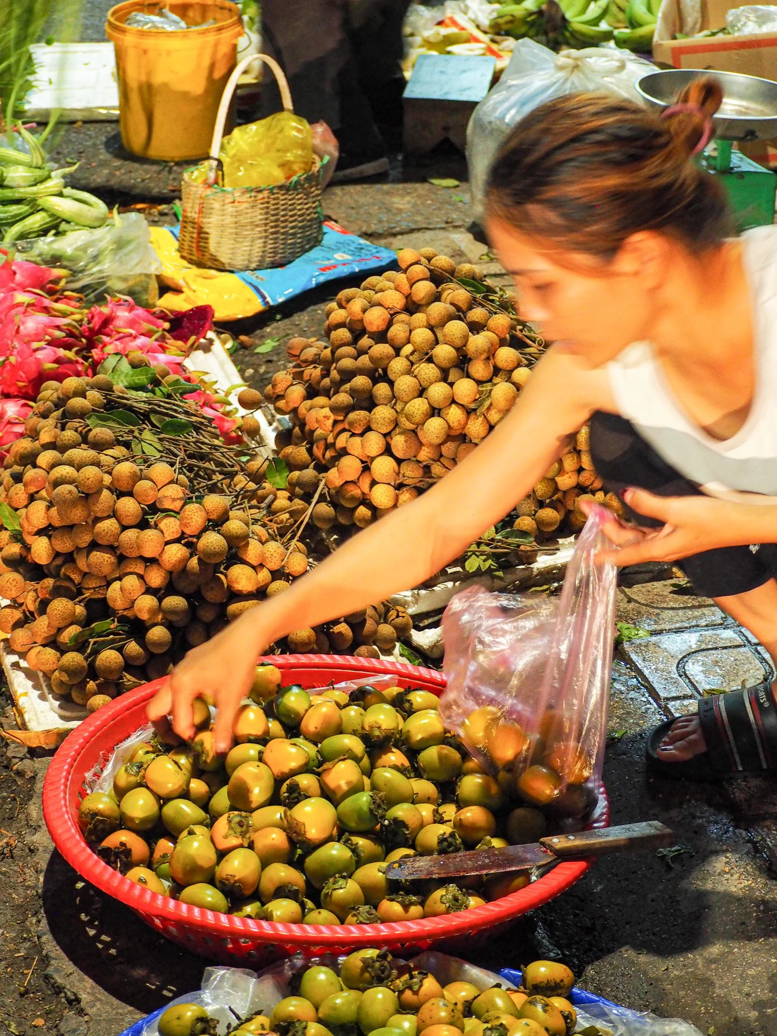 Frau beim Einkauf auf einem Markt, Auswahl von lokalen Früchten, inklusive Passionsfrüchten, am Straßenmarkt verkauft.