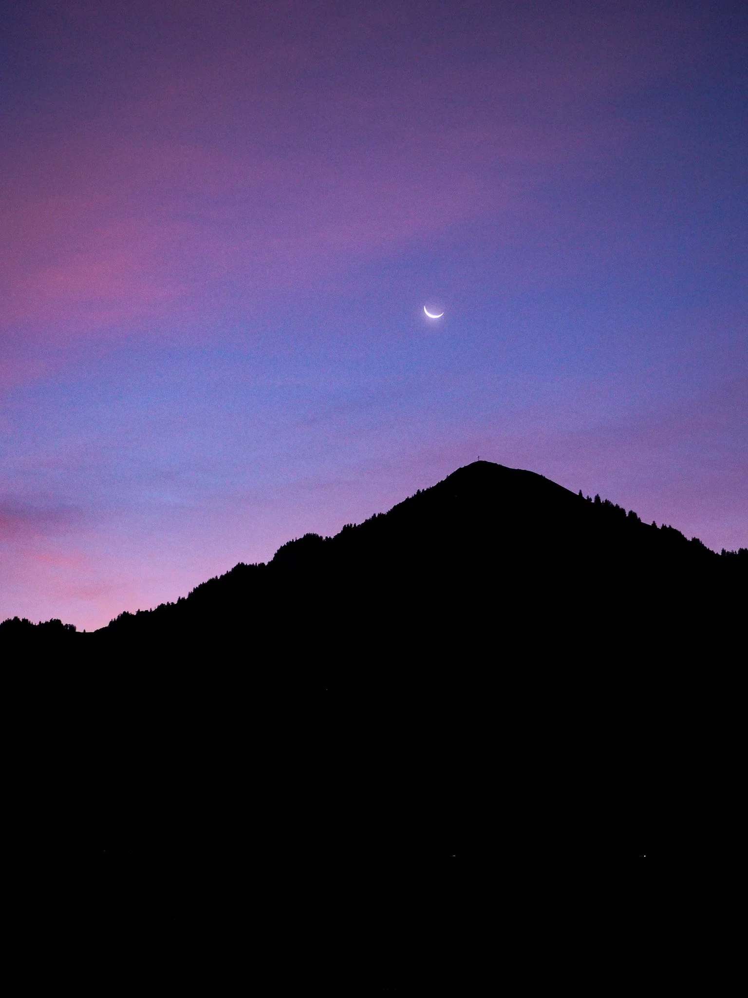 Bergsilhouette bei Sonnenuntergang mit Himmel in Pastellfarben und Mondsichel