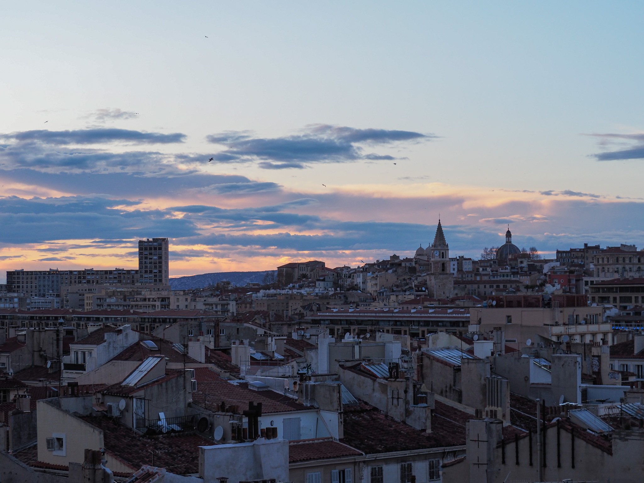 Stadtbügel mit historischen und modernen Gebäuden bei Sonnenuntergang, Wolken im Himmel