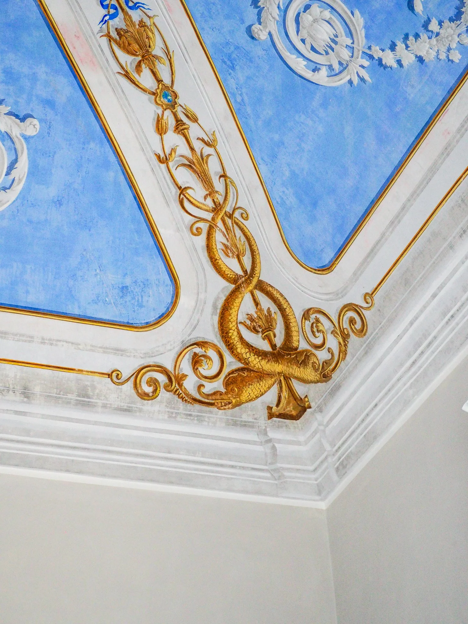 Deckenfresko mit goldenen Ranken und Pflanzenmotiven auf blauer und weißer Decke.