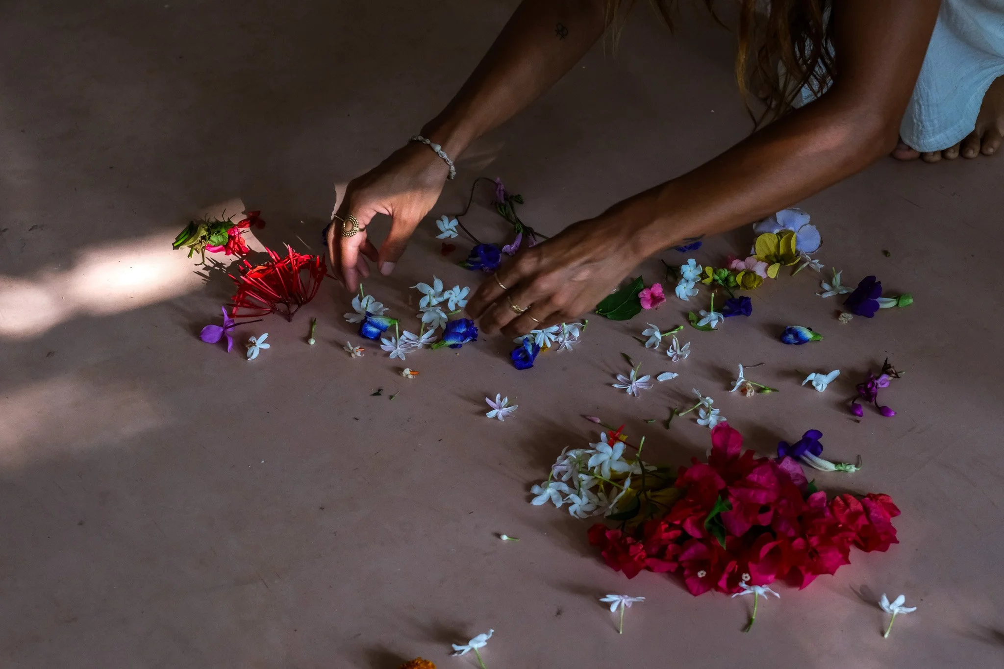 Eine Person ordnet bunte Blumen auf dem Boden an.