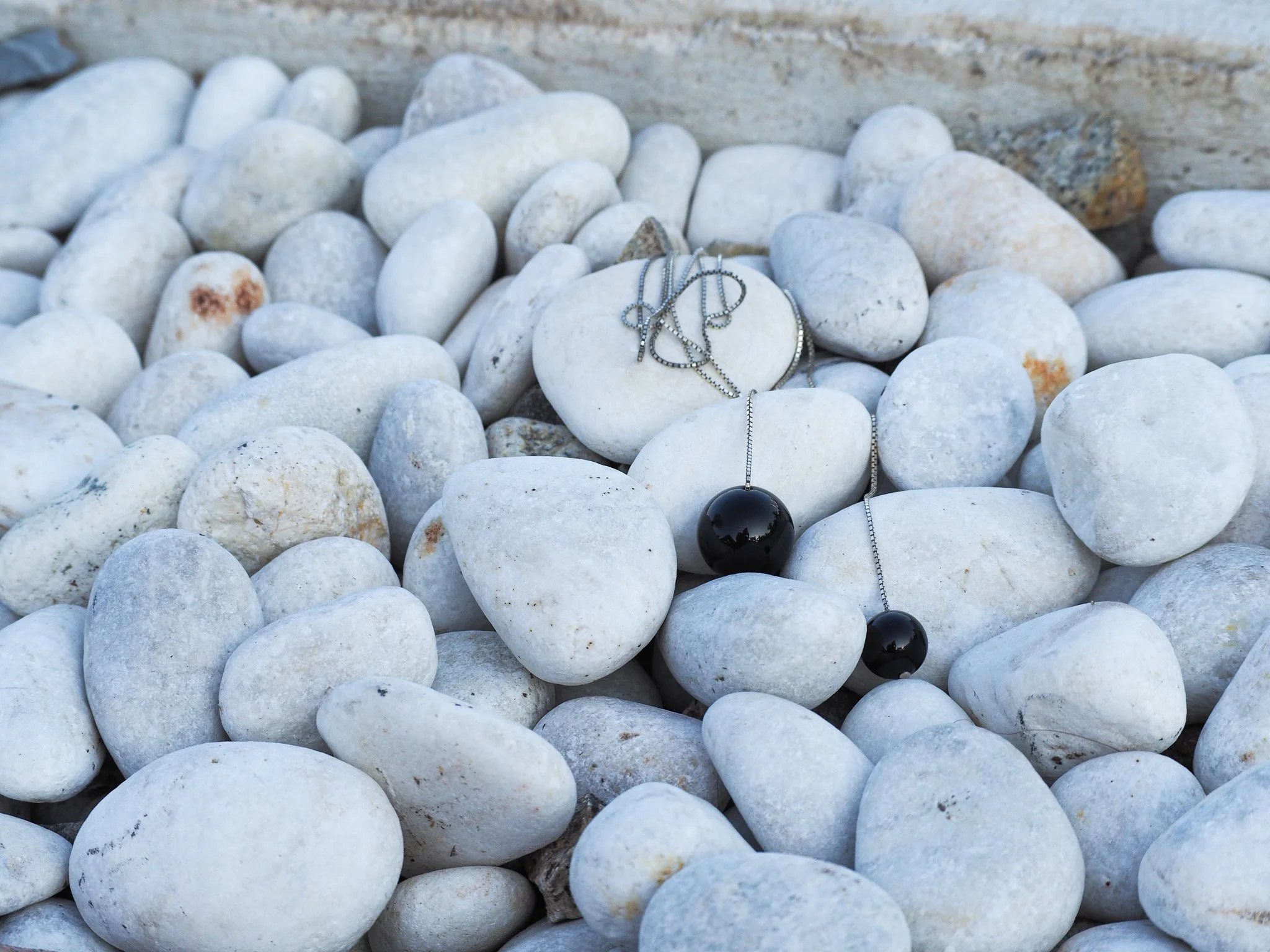 Schwarz-silberne Halskette mit schwarzen Kugeln auf weißen Steinen.
