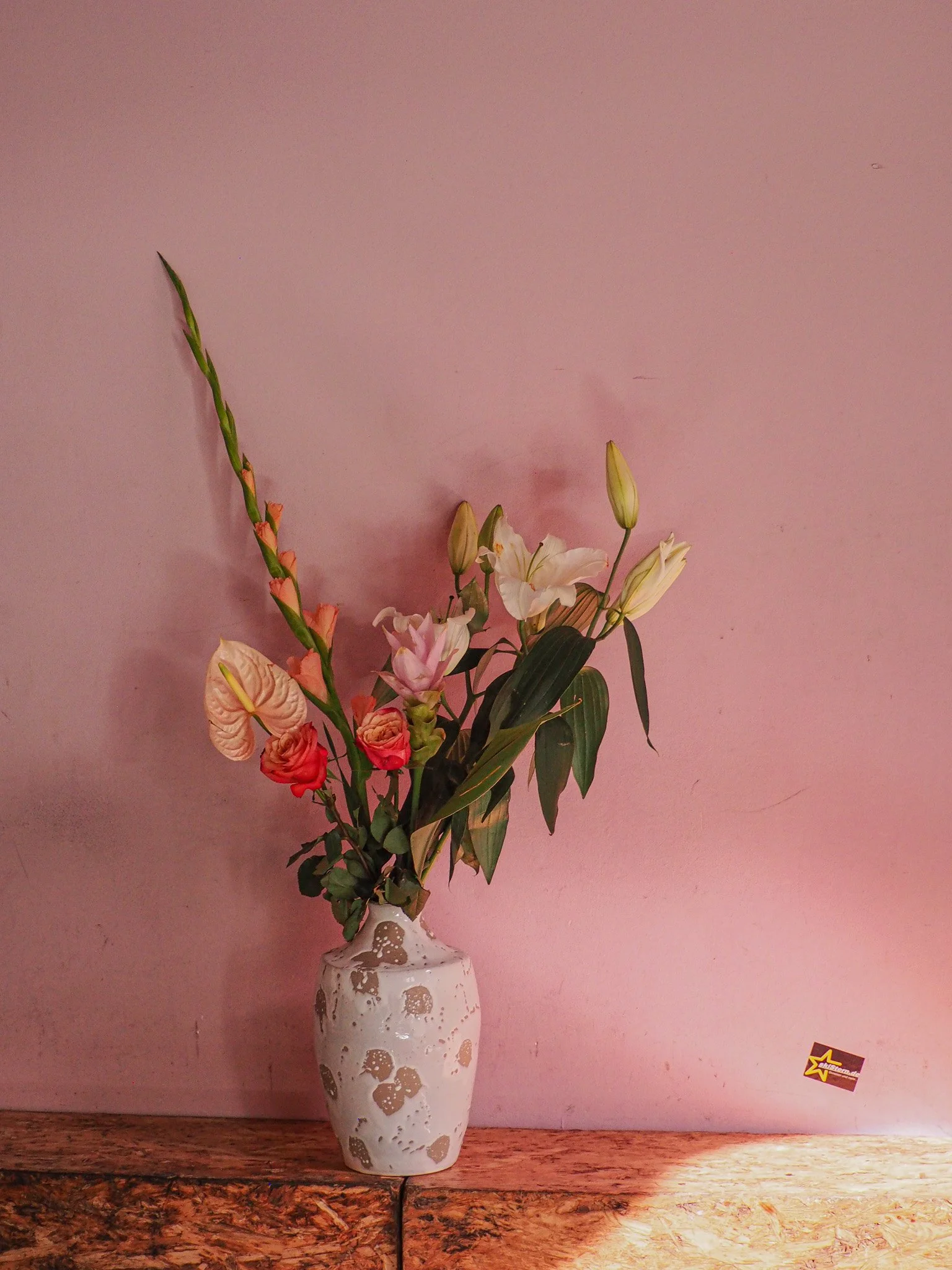 Bunte Blumen in einer weißen Vase vor einer rosa Wand