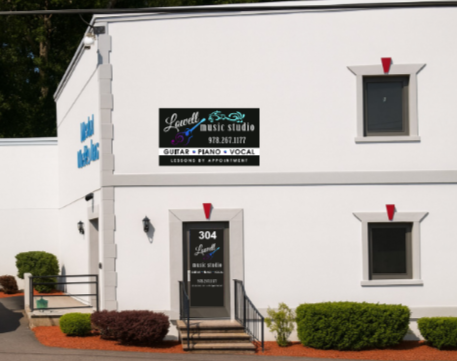 Exterior of a white building with signs for Lowell Music Studio, showing the address 304 and indicating services for guitar, piano, and vocals.