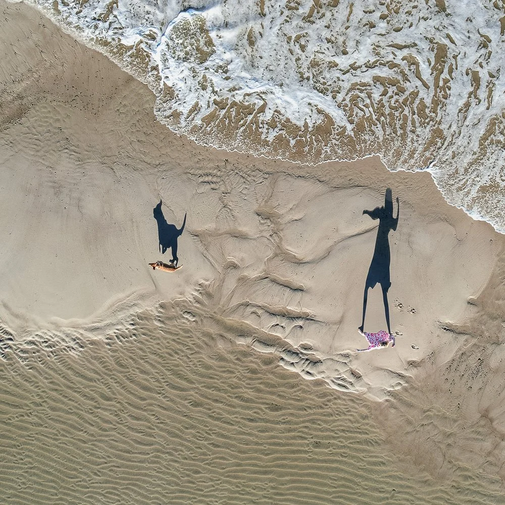 Luftaufnahme eines Sandstrandes mit Brandung und zwei langen Schatten von Personen – Drohnenfotografie an der Nordsee