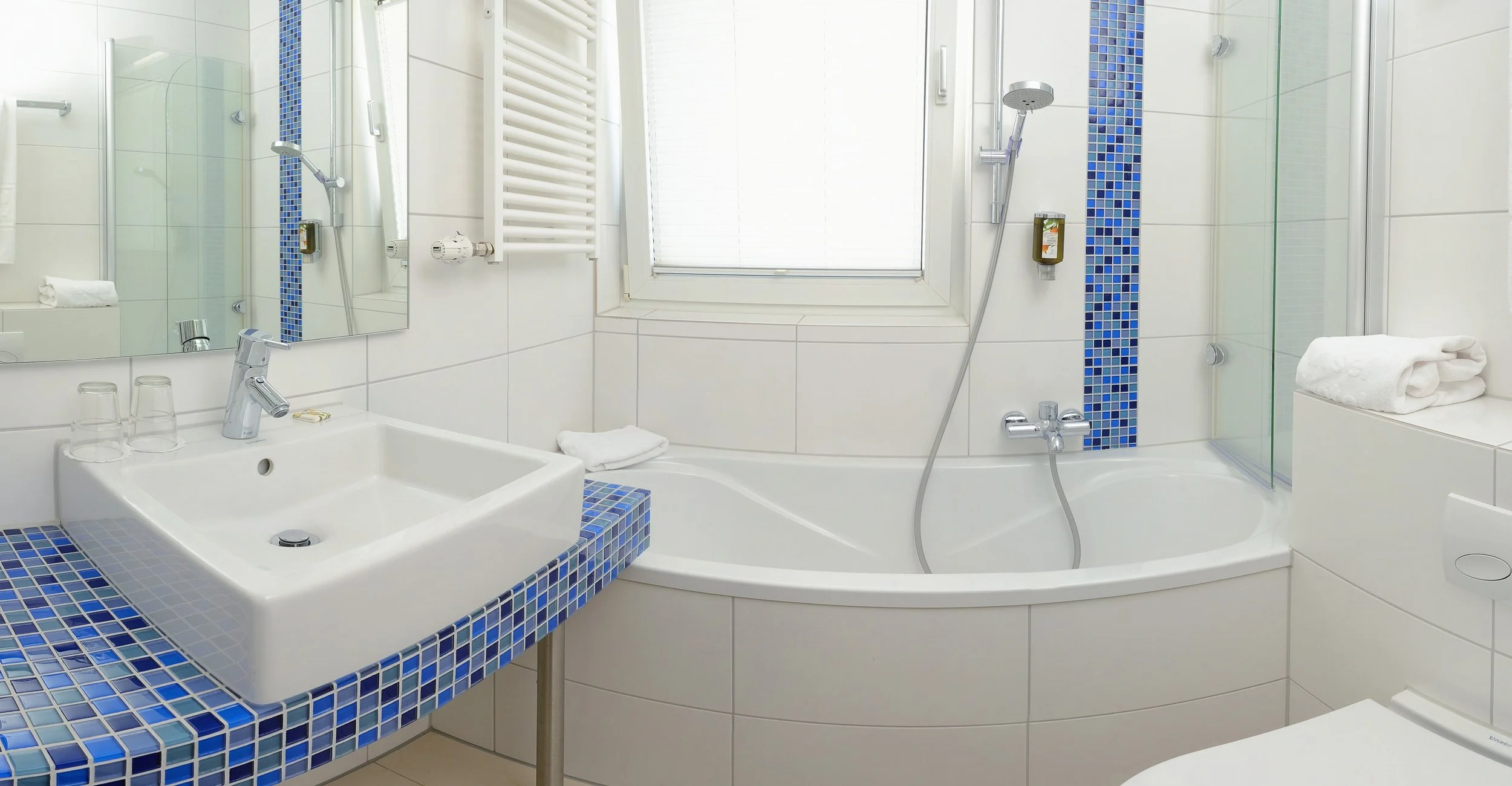 Modernes Badezimmer mit blauem Mosaik, Eckbadewanne und Waschtisch – Innenarchitektur-Fotografie