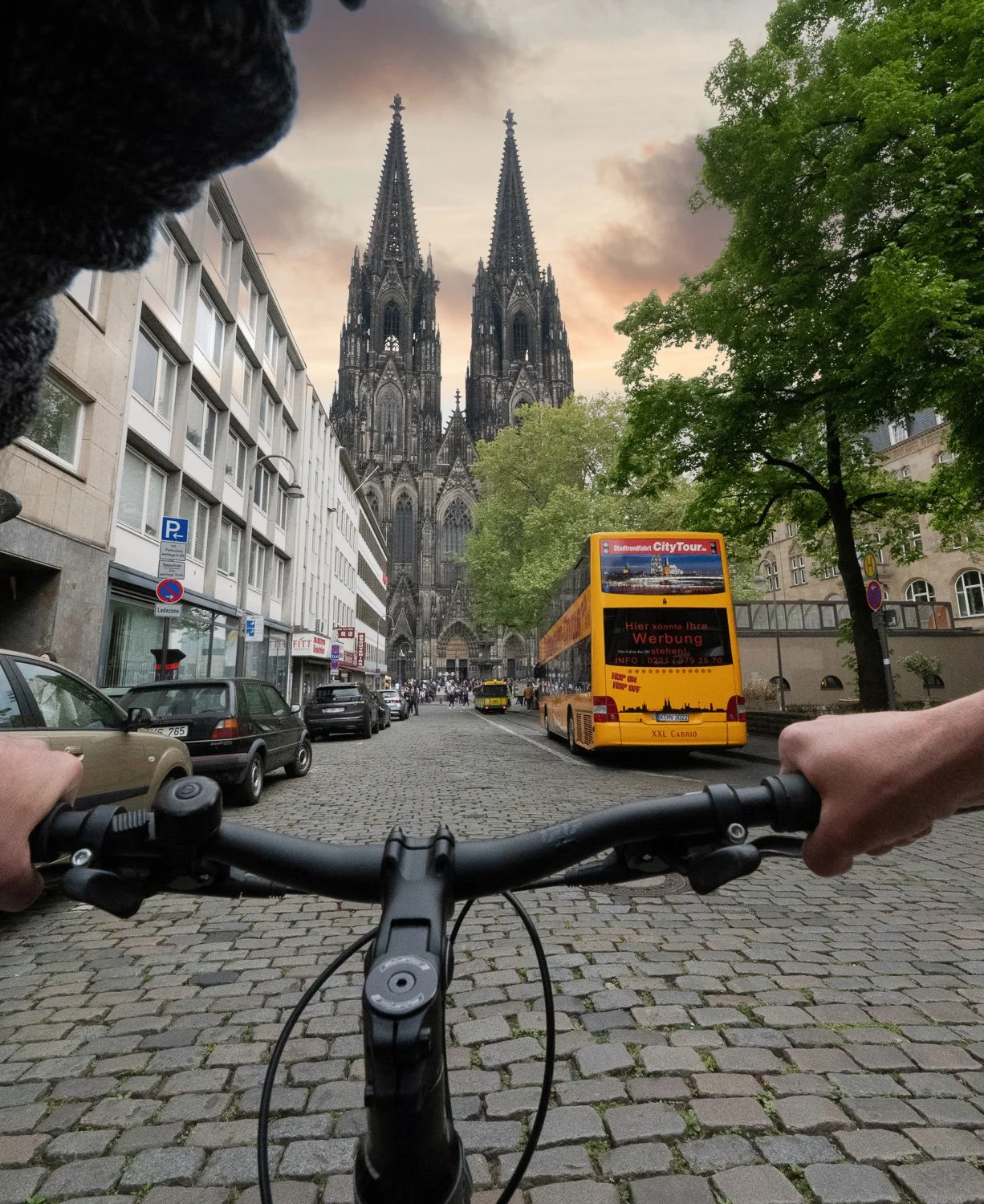Blick über den Fahrradlenker auf den Kölner Dom mit gelbem City-Tour-Bus – Tourismusfotografie in Köln