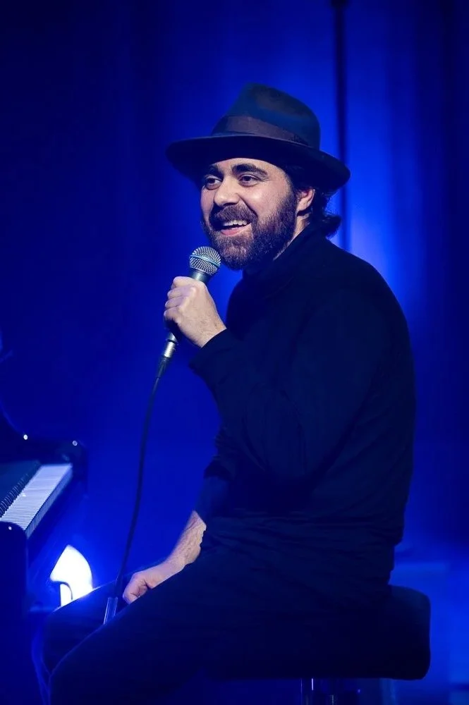 Sänger mit Hut beim Live-Auftritt in blauem Bühnenlicht.