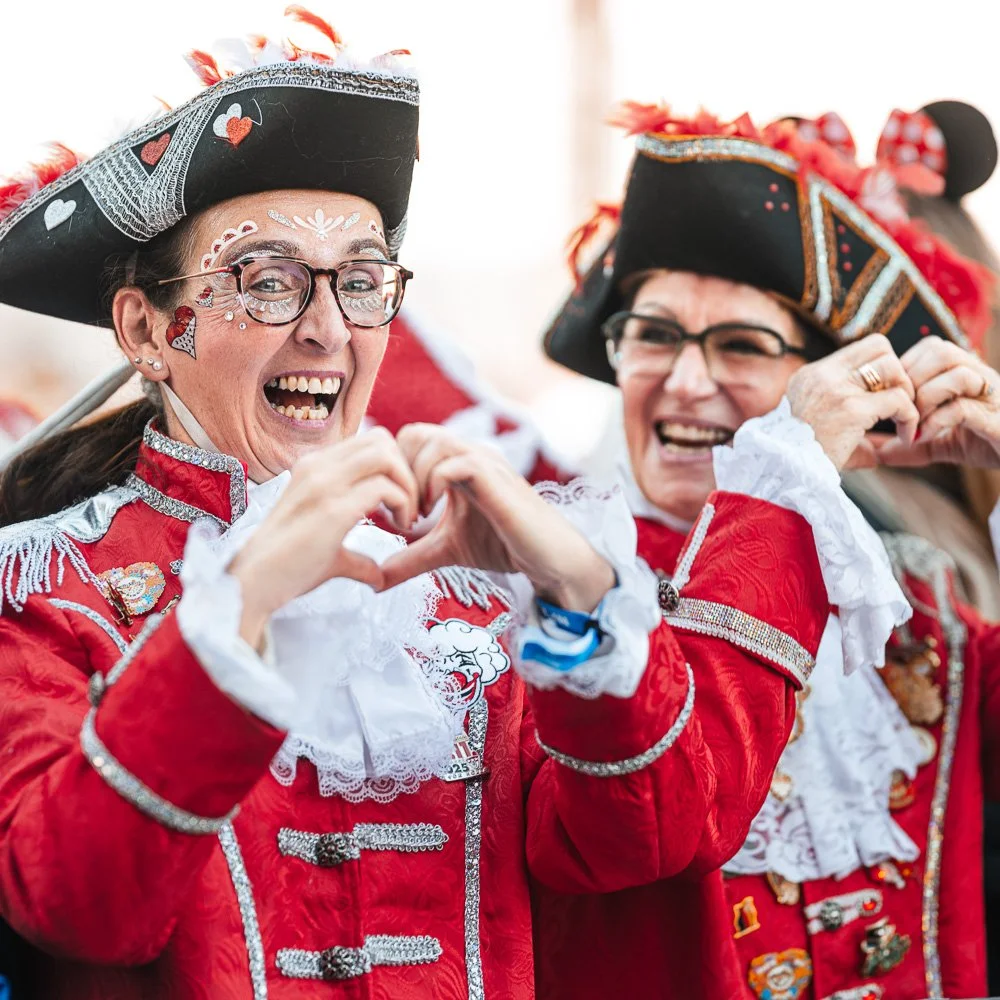 Zwei Gardisten in roter Uniform formen mit den Händen ein Herz.
