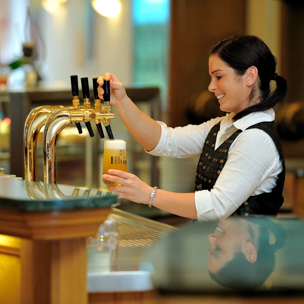 Mitarbeiterin zapft ein Bier an der Hotelbar – Hotel- und Servicefotografie in Köln.