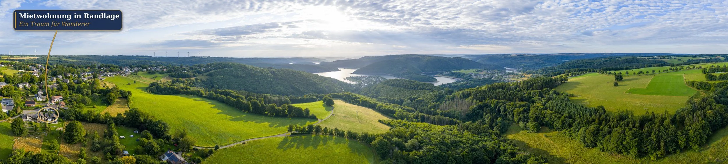 Drohnenpanorama einer hügeligen Eifel-Landschaft mit Stausee, eine Ferienwohnung in Randlage markiert – Luftbild-Panorama für Tourismus und Ferienimmobilien