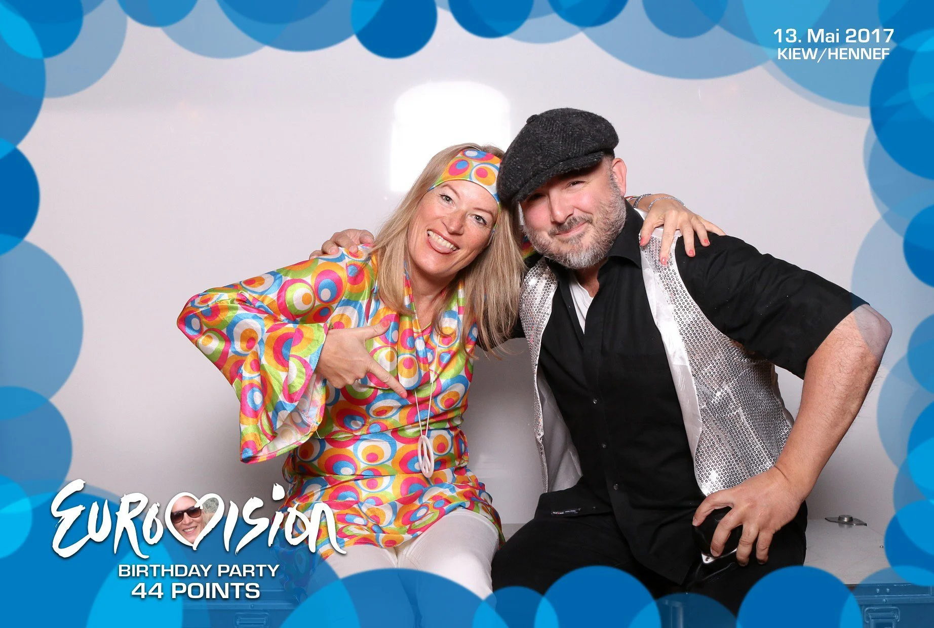 Paar vor buntem Hintergrund in der Fotobox auf einer Mottoparty