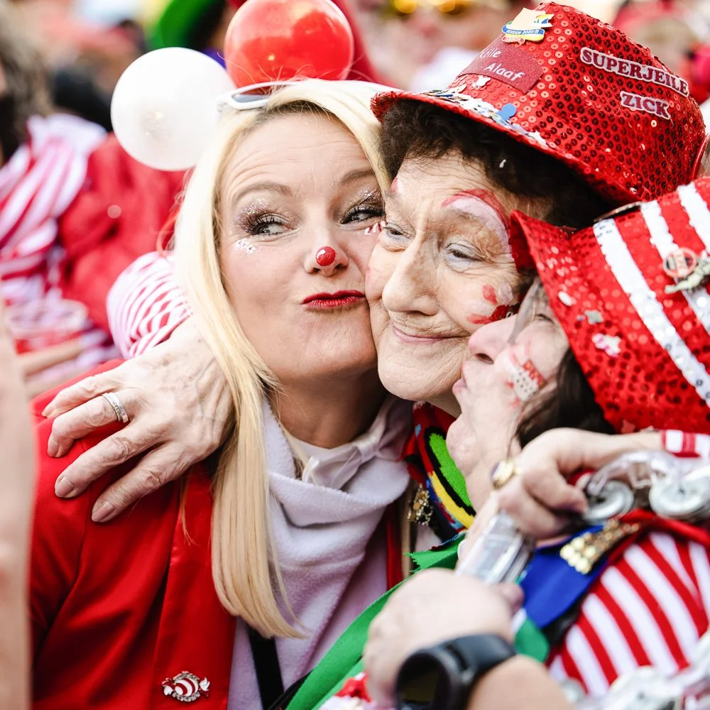 Feiernde Jecken in rot-weißen Kostümen beim Kölner Karneval.