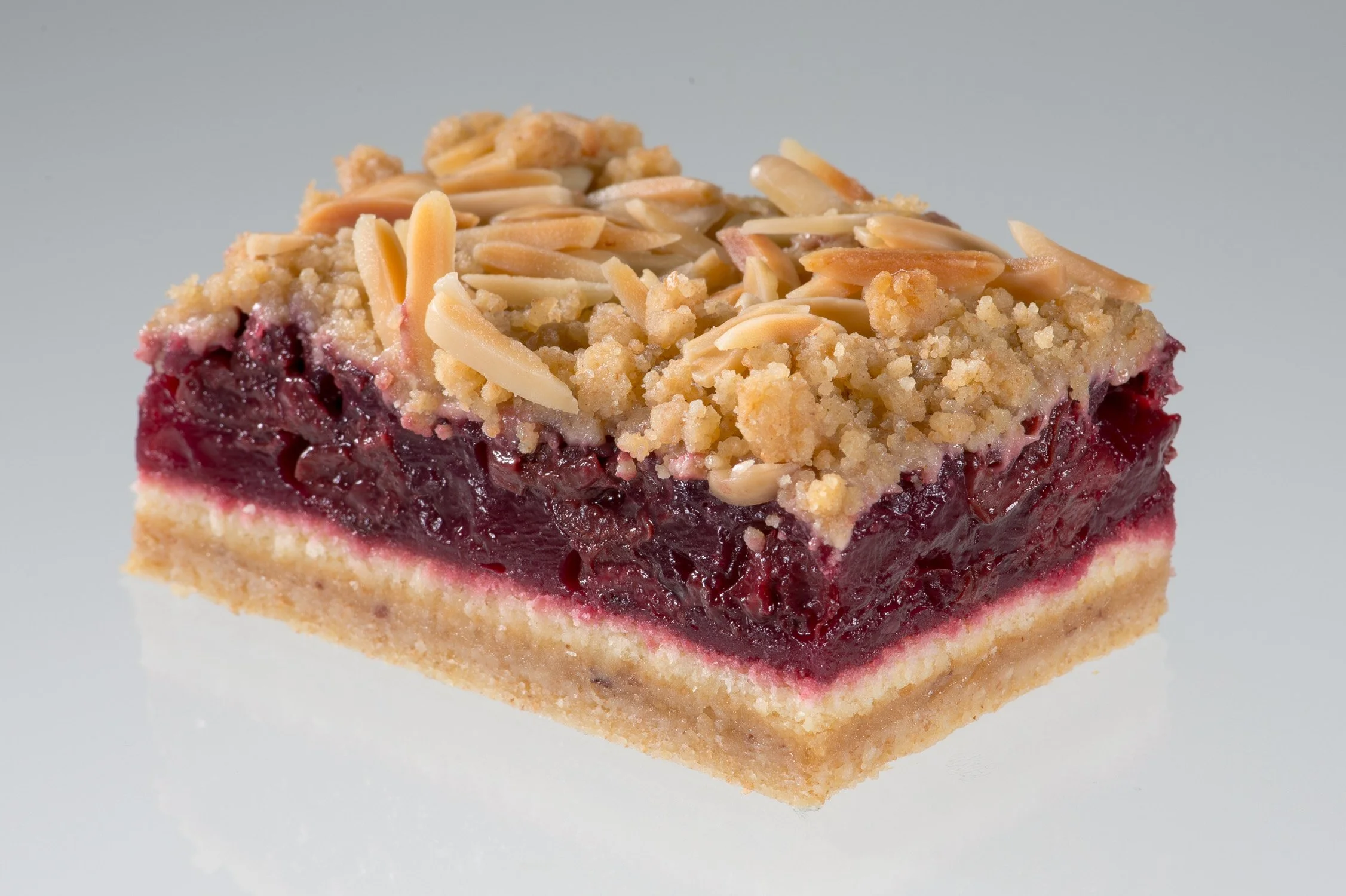 Kuchenstück mit Mandelkruste und fruchtiger Füllung, freigestellt – Food-Produktfotografie für eine Konditorei