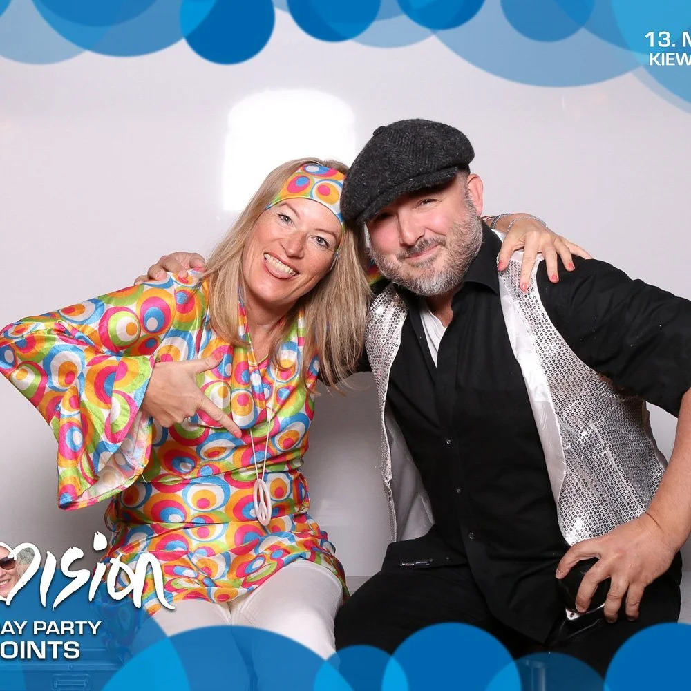 Paar vor buntem Hintergrund in der Fotobox auf einer Mottoparty