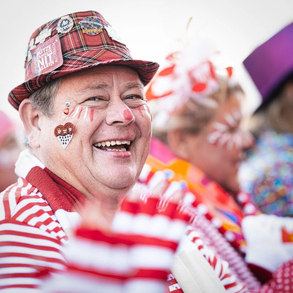 Lachender Jeck mit Schminke und rot-weißem Kostüm beim Karneval.