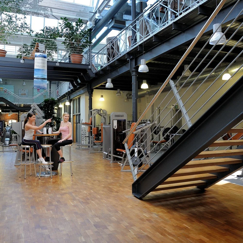 Loft-artige Industriehalle mit Stahltreppe und Sitzbereich unter Glasdach – Industrie- und Architekturfotografie in Hennef