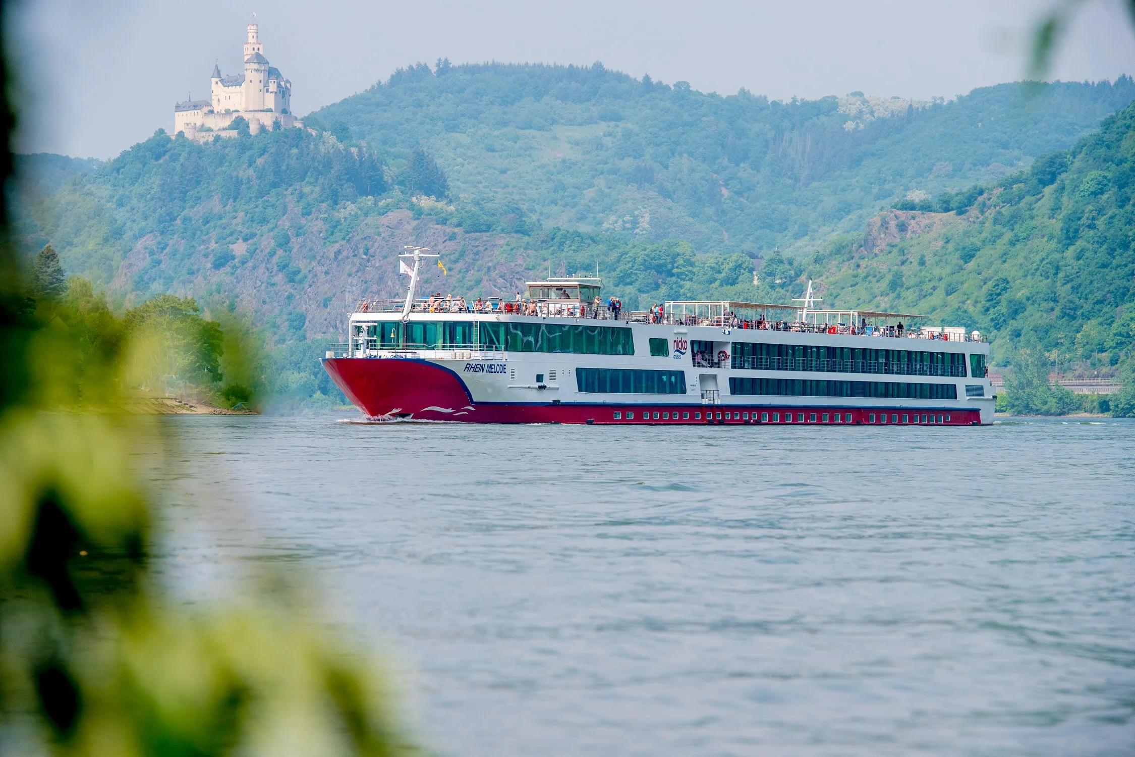 Flusskreuzfahrtschiff auf dem Rhein vor Burgkulisse – Tourismus- und Hotelfotografie zur Lage in Königswinter.