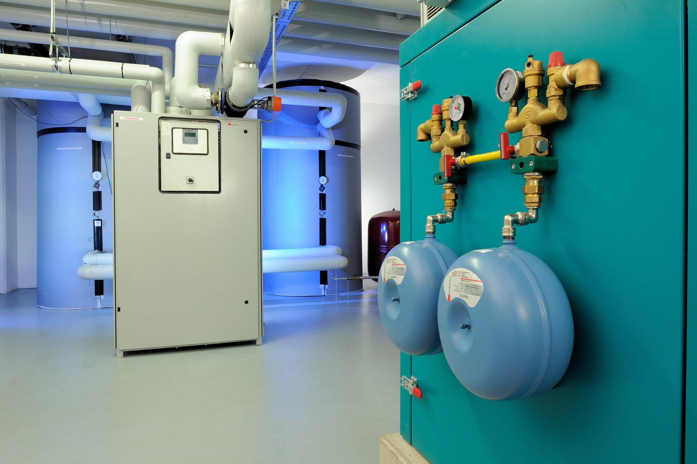 Technische Anlage mit blau beleuchteter Maschine und Messing-Armaturen im Vordergrund – Industriefotografie in Hennef