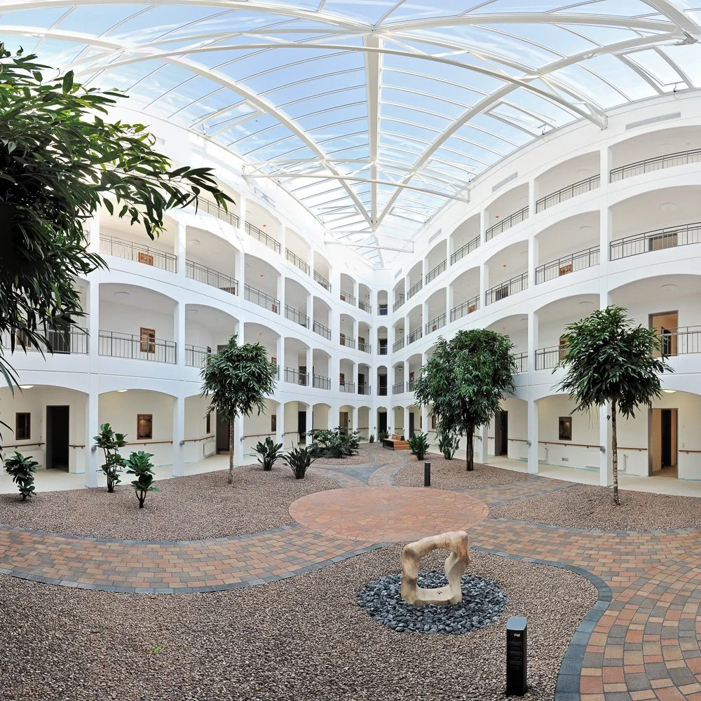 Überdachter Innenhof mit weißer Pergola-Konstruktion und Pflasterung – Architekturfotografie eines Glasdach-Atriums