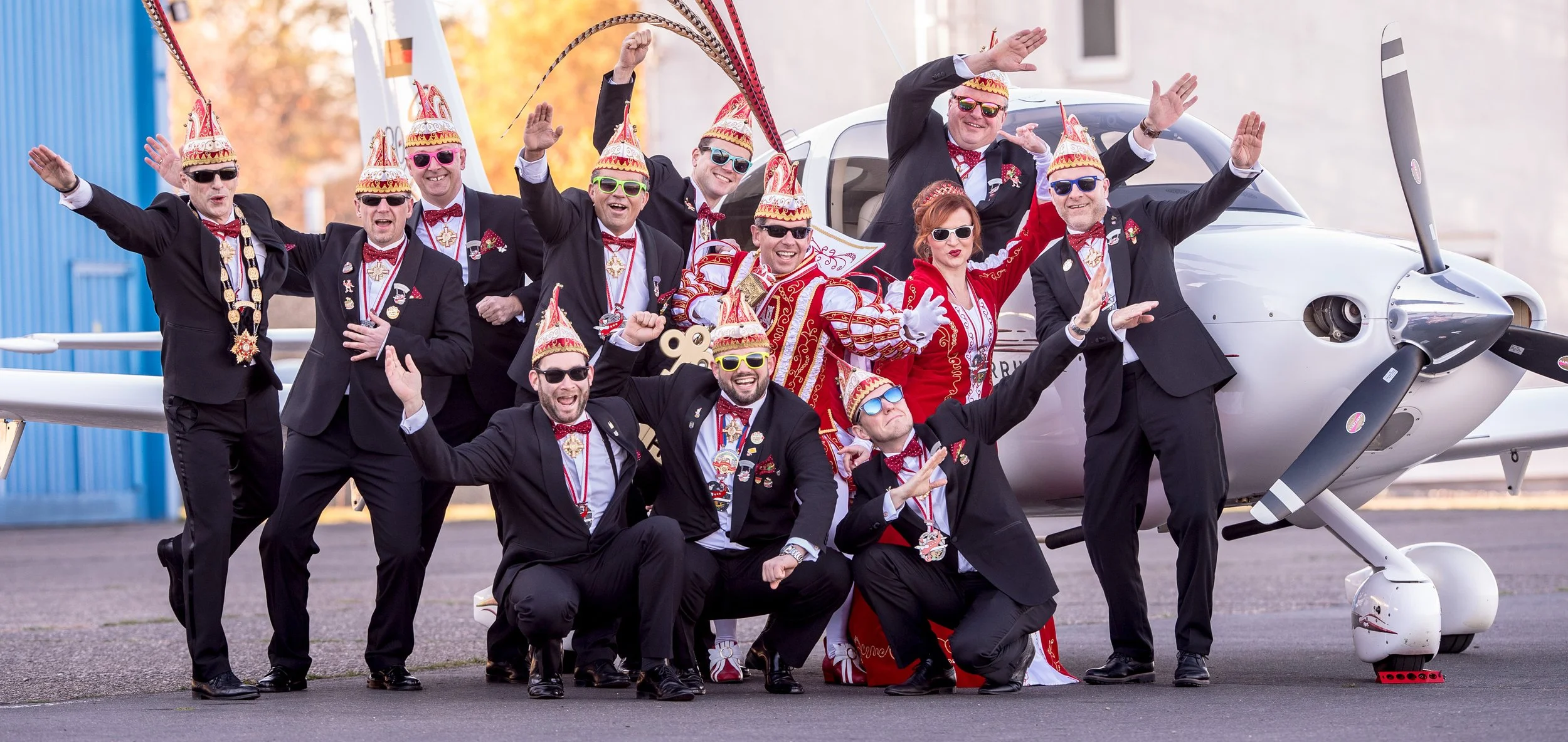 Gruppenbild der Karnevalsgesellschaft „Hennefer Erste" mit ihrem Prinzenpaar vor einem Flugzeug.