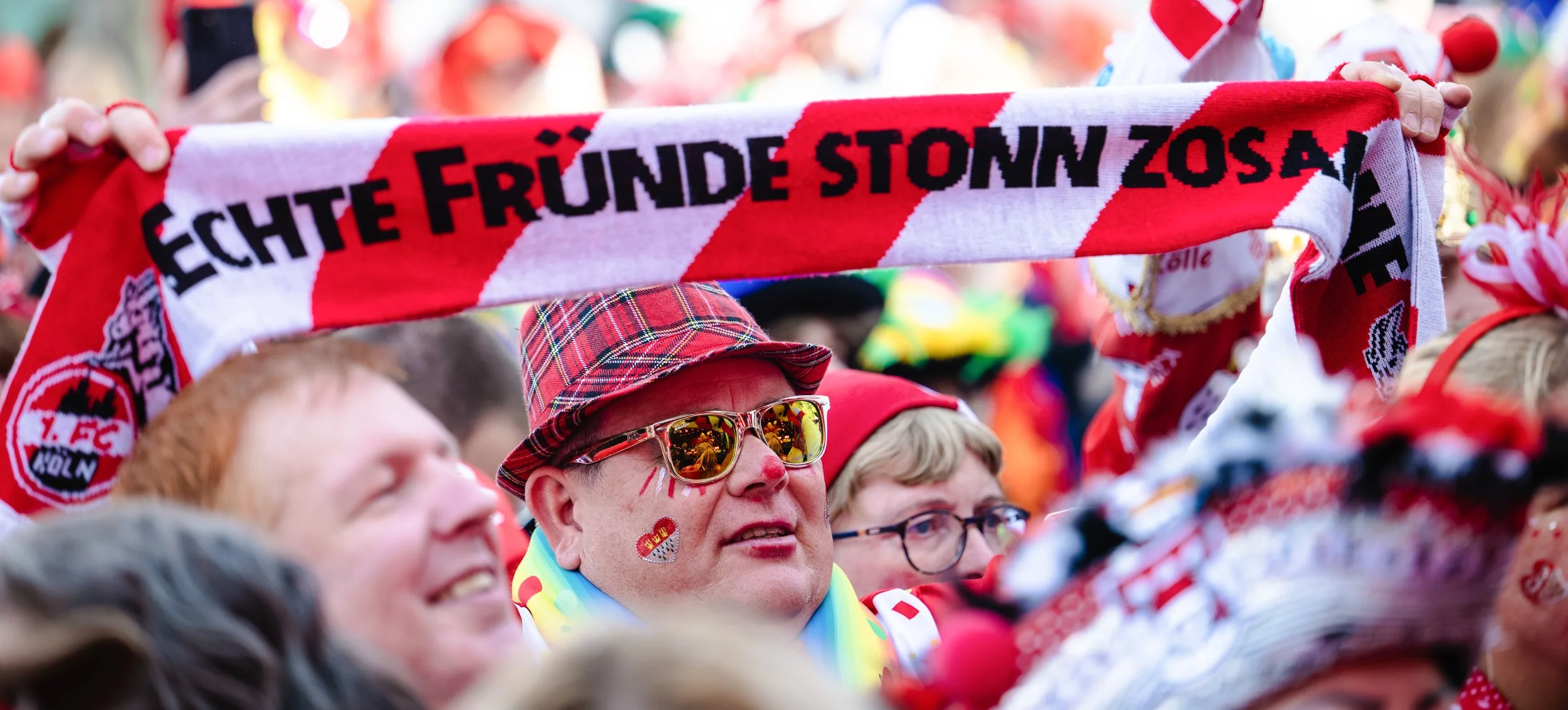 Feiernde Karnevalisten mit einem Banner in der Menge.