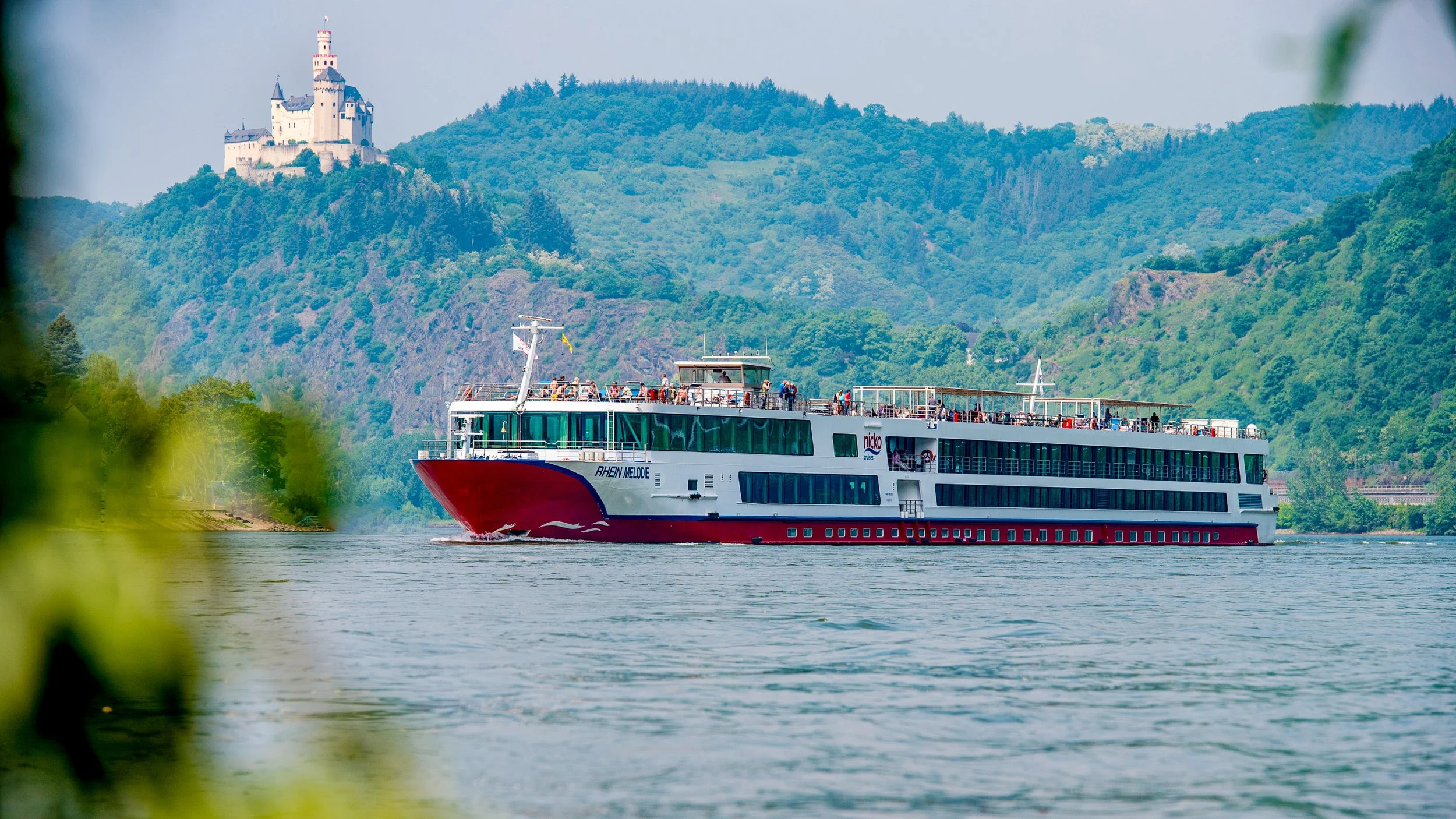 Rot-weißes Flusskreuzfahrtschiff auf dem Rhein unterhalb der Marksburg – Tourismusfotografie im Rheintal