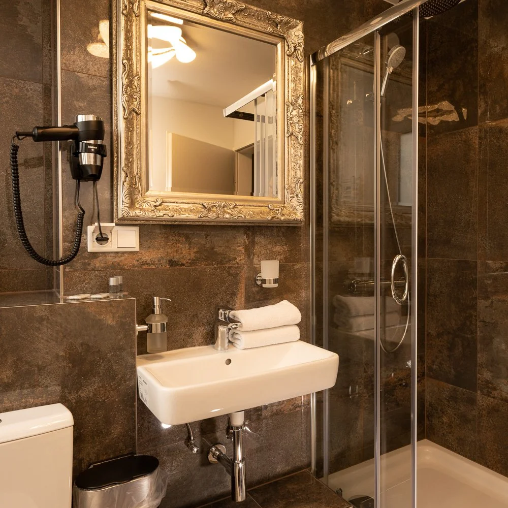 Badezimmer mit Spiegel und verglaster Dusche – Hotelfotografie in Hennef.