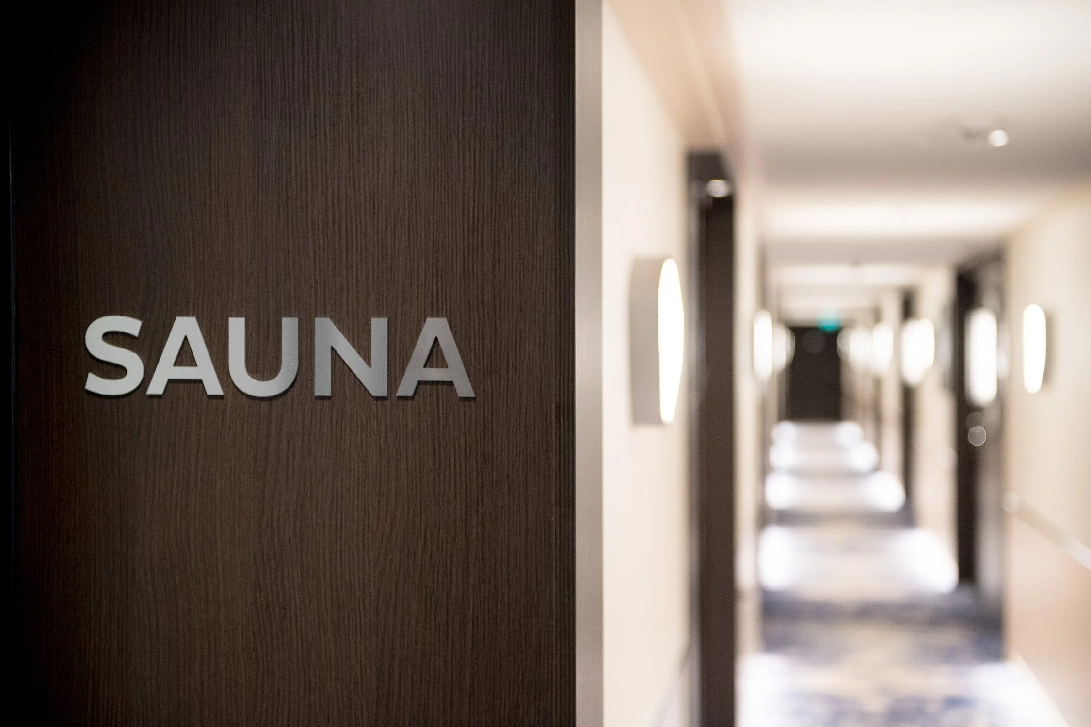Wellnessbereich eines Hotels mit „SAUNA"-Schild und beleuchtetem Flur – Hotelfotografie