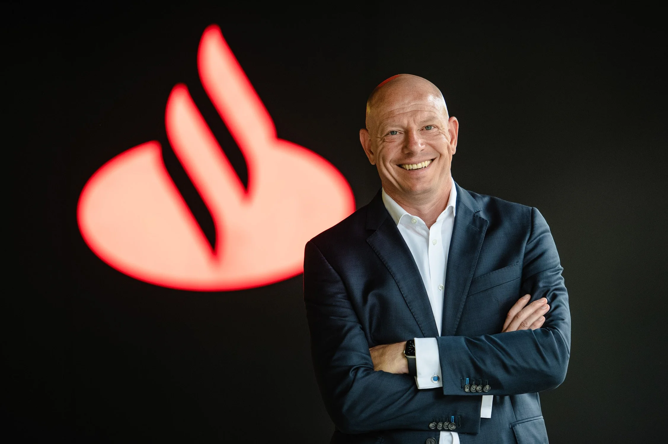 Businessportrait einer Führungskraft vor leuchtendem Unternehmenslogo – moderne Managementfotografie.