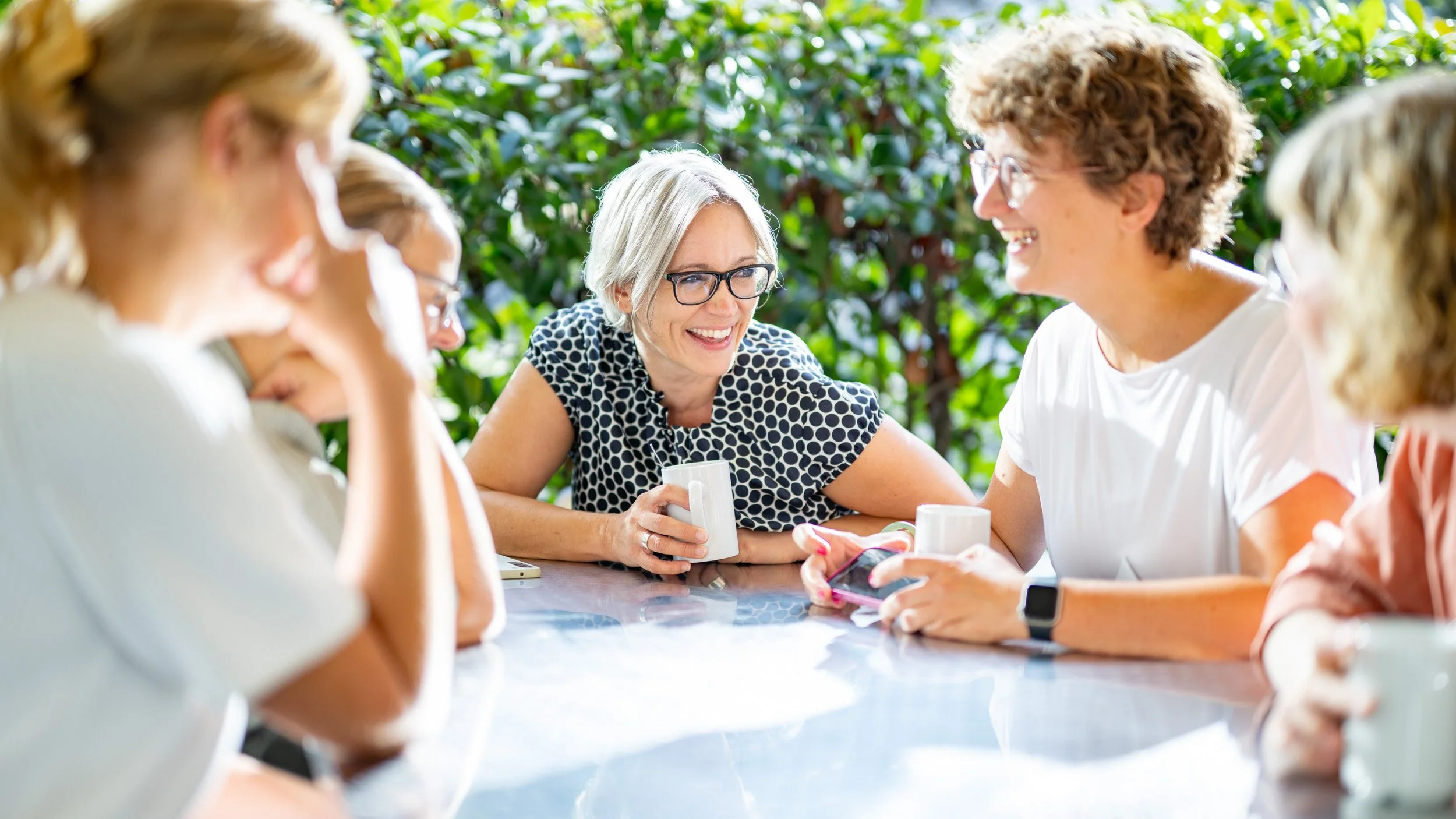 Entspannte Gesprächsrunde bei Kaffee im Freien während eines Firmen-Sommerfestes
