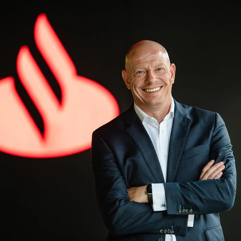 Businessportrait einer Führungskraft vor leuchtendem Unternehmenslogo – moderne Managementfotografie.