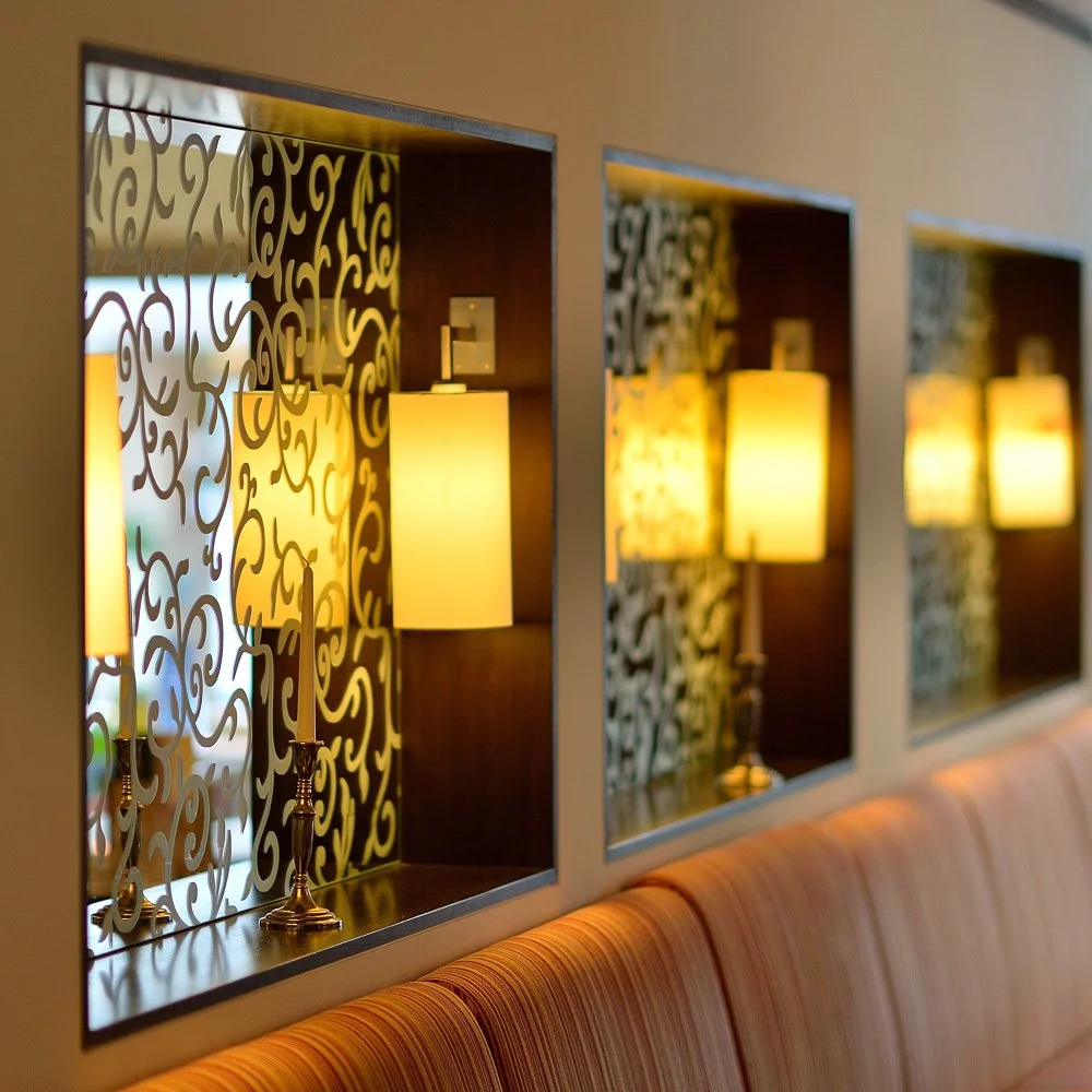 Hinterleuchtete Ziermuster-Lichtwand mit Wandleuchten in einem Restaurant – Innenarchitektur-Fotografie