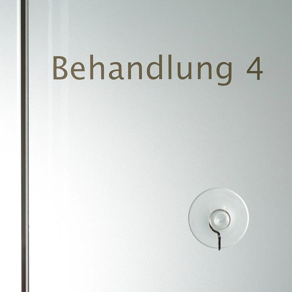 Milchglastür mit der Beschriftung „Behandlung 4“ – Unternehmensreportage einer Praxis in Brühl.