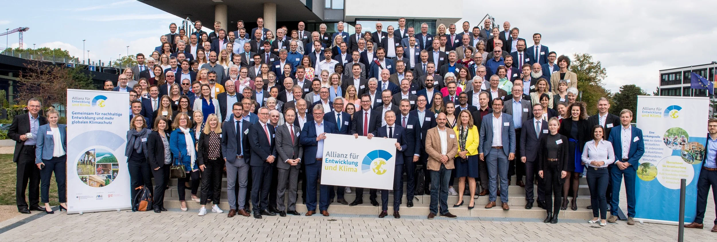Großes Gruppenfoto aller Teilnehmenden der Klimakonferenz „Allianz für Entwicklung und Klima" im Freien – Tagungsfotografie in Bonn.